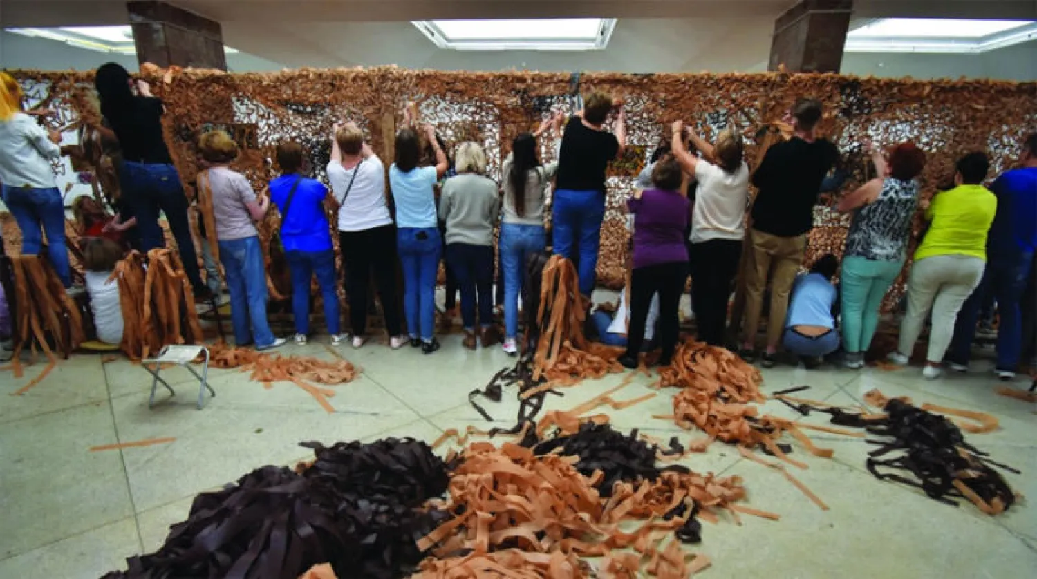 أوكرانيون يعدّون في لفيف أمس شبكات للتمويه ليستخدمها جيش بلادهم في الحرب (رويترز)