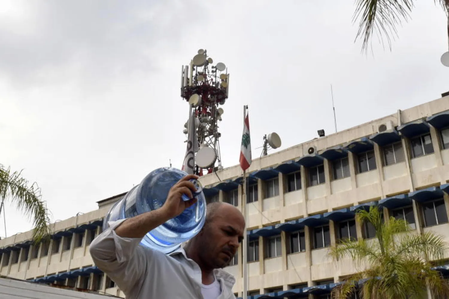 رجل يحمل عبوة مياه يمر امام مبنى هيئة أوجيرو (إ.ب.أ)