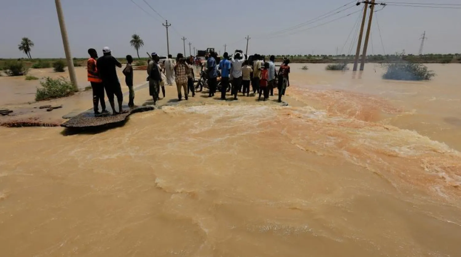 People stand amidst the floodwaters in Al-Managil locality in Gezira state, Sudan, August 23, 2022. (Reuters)
