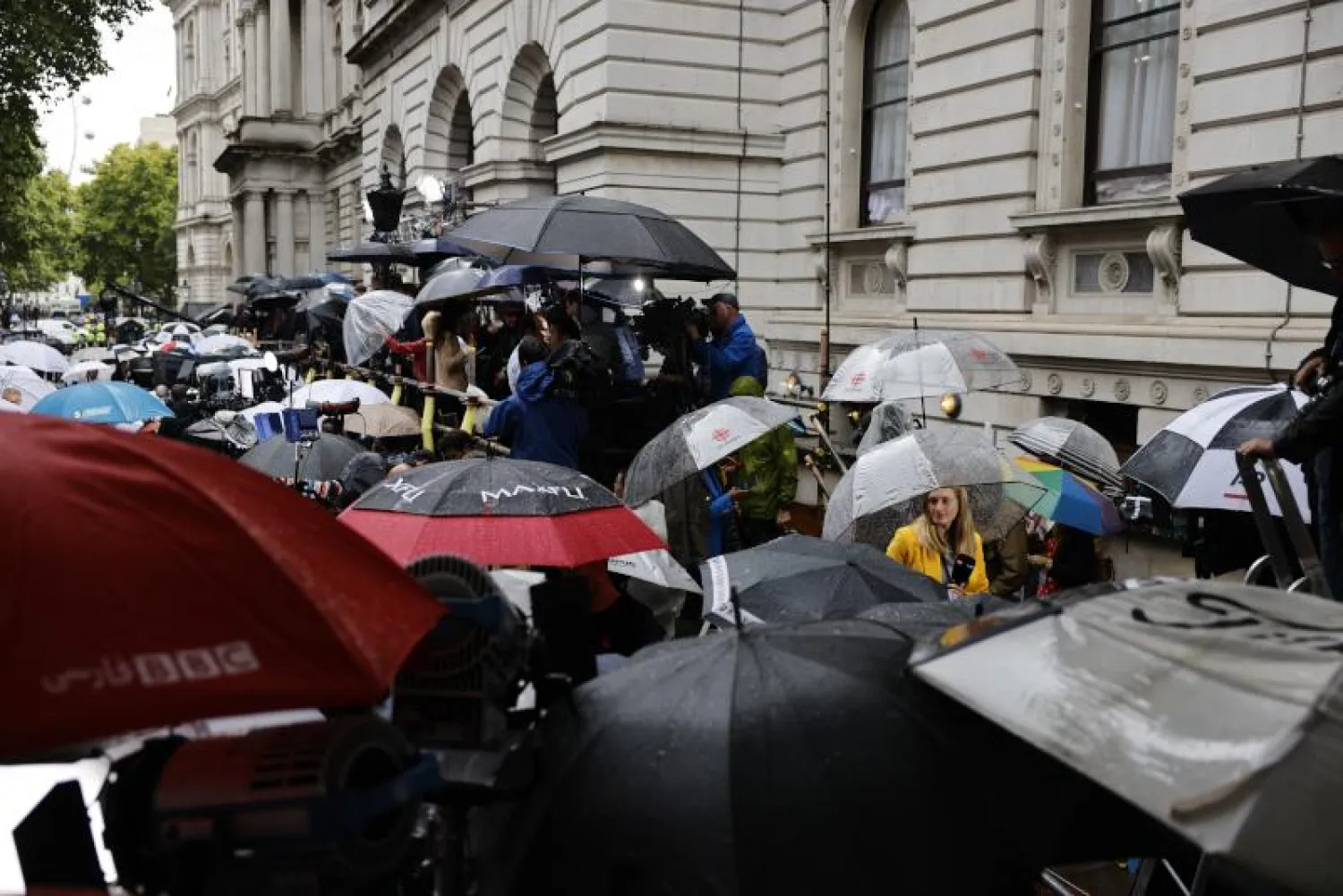 صحافيون ومؤيدون ينتظرون تحت المطر وصول رئيسة الوزراء ليز تراس إلى 10 داوونغ ستريت في لندن (إ.ب.أ)