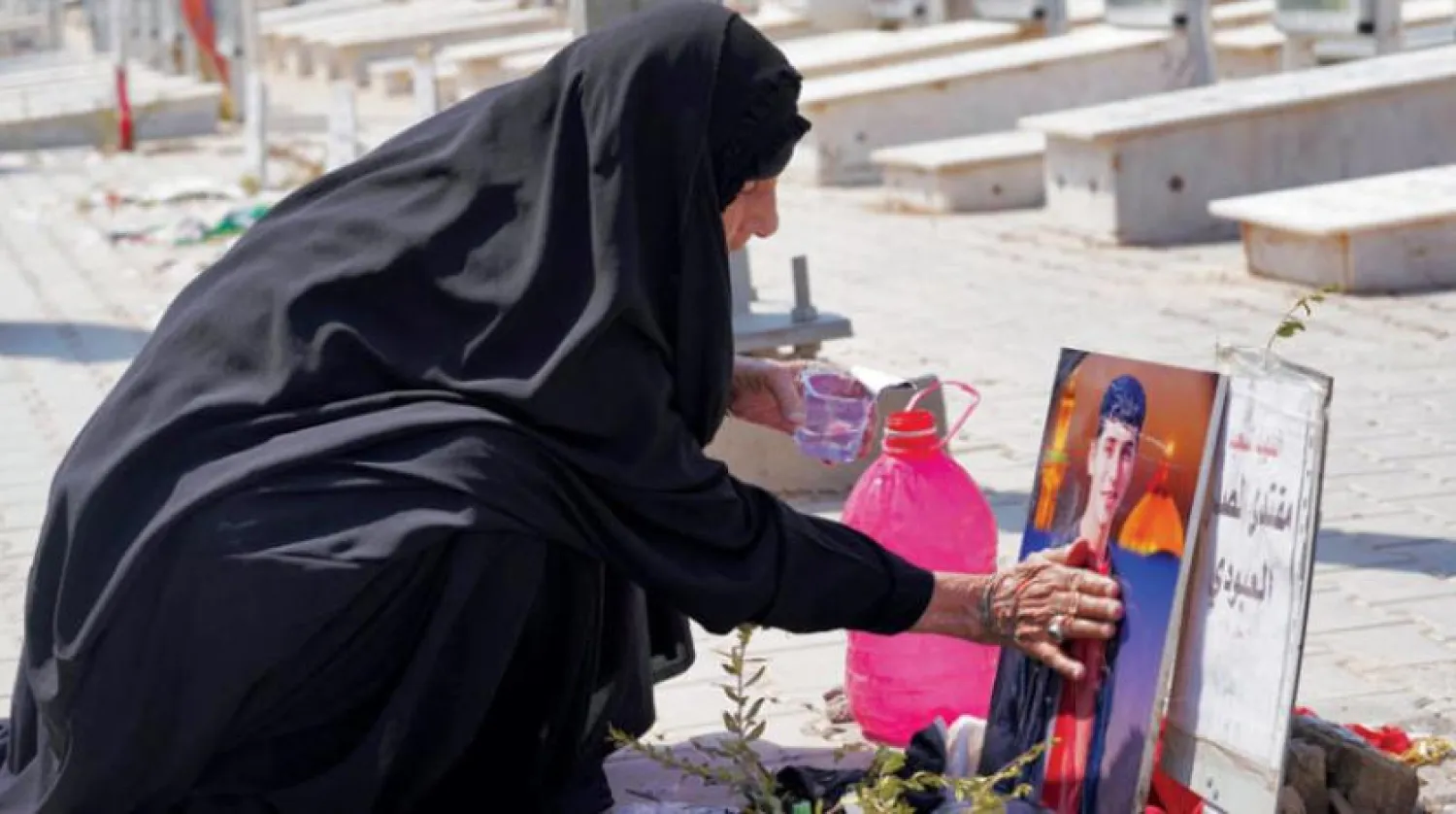 2004 yılında Şii lider Mukteda es-Sadr liderliğindeki Mehdi Ordusu savaşçılarının defnedildiği Necef'teki bir mezarlıkta kabir ziyaretinde bulunan bir kadın (AFP)