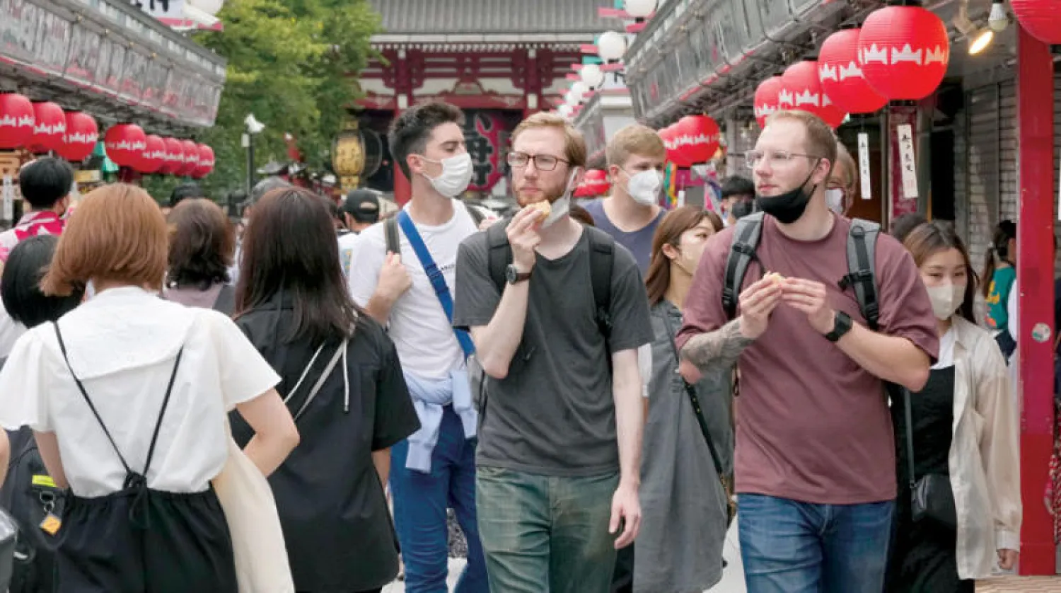 سياح أجانب يسيرون أثناء إعلان اليابان تخفيف قيود «كورونا»، وسط طوكيو، أول من أمس (إ.ب.أ)
