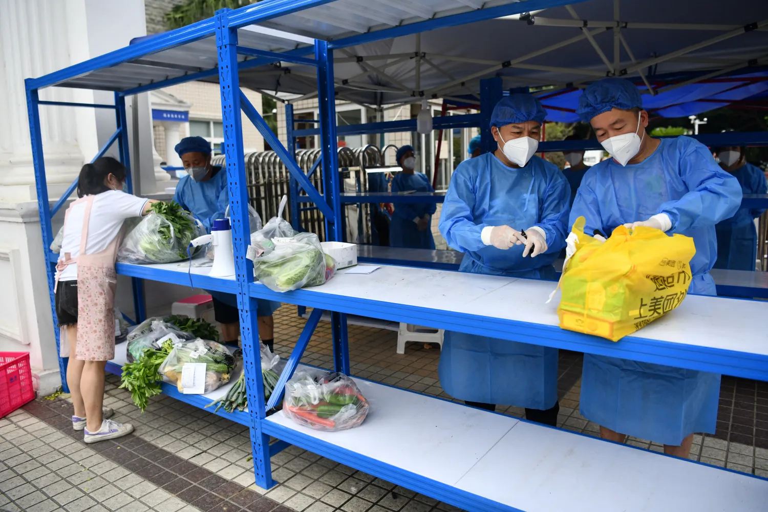 Workers in protective suits prepare to deliver food supplies placed on a rack outside a residential compound to its residents, amid a lockdown to curb the coronavirus disease (COVID-19) outbreak in Chengdu, Sichuan province, China September 2, 2022. cnsphoto via REUTERS
