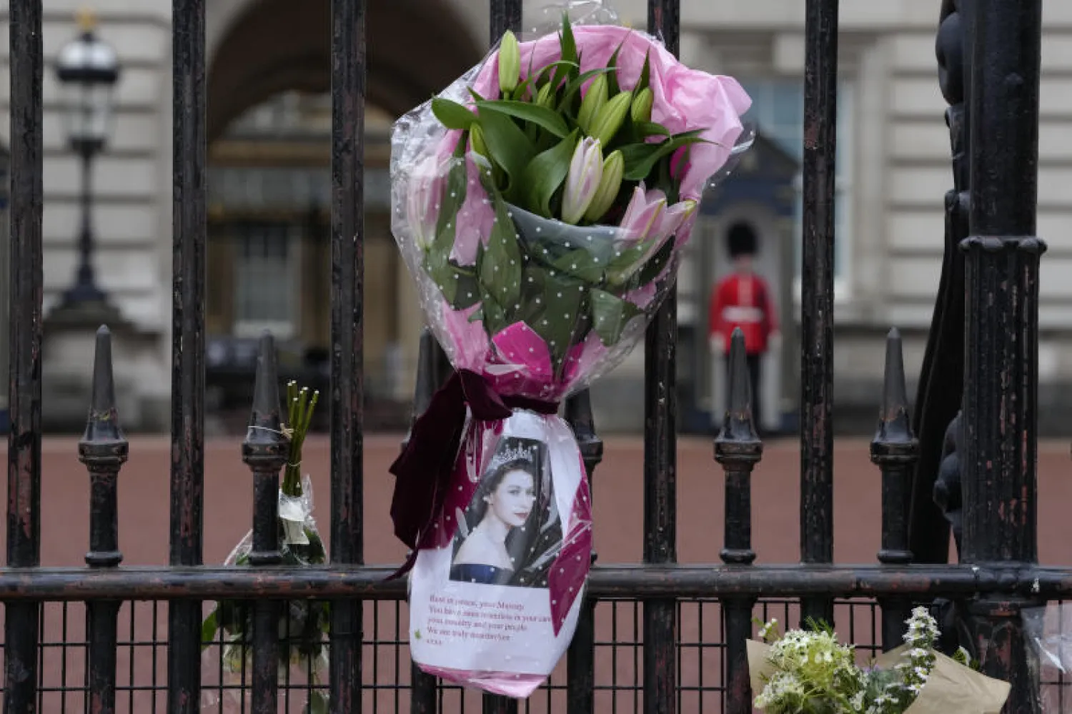 زهور ورسالة خارج قصر باكنغهام في رثاء الملكة إليزابيث الثانية  (أ.ب)