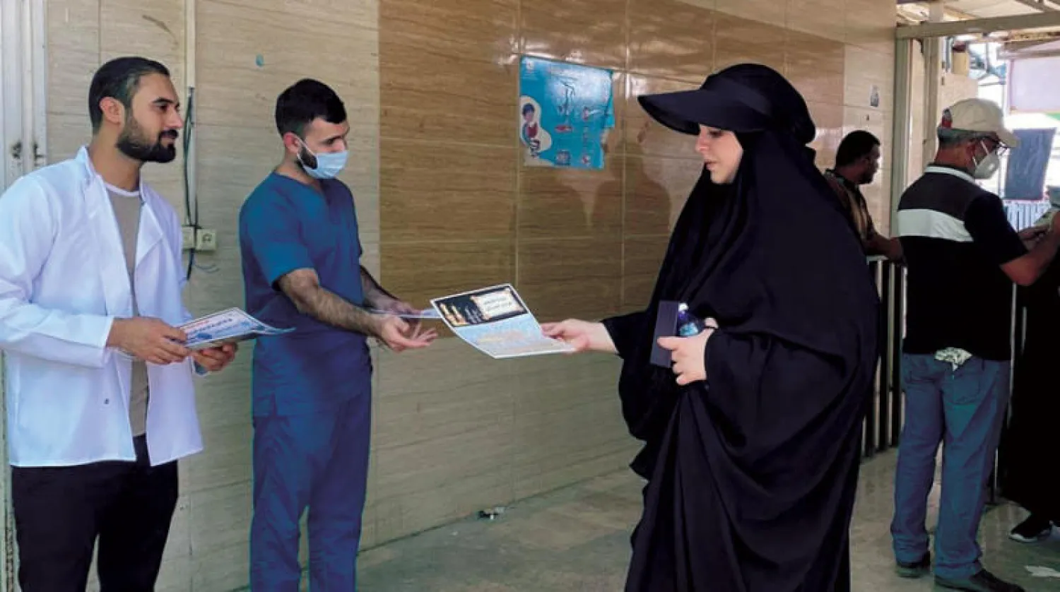 موظفو الصحة في معبر «مهران» يقدمون بطاقة إرشادات صحية للزائرين الإيرانيين (الشرق الأوسط)