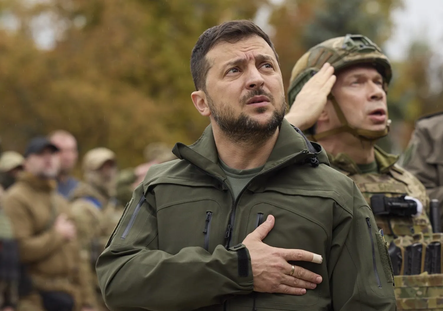 In this photo provided by the Ukrainian Presidential Press Office, Ukrainian President Volodymyr Zelenskyy, center, sings the Ukrainian national anthem during his visit to the city of Izium, Kharkiv region, Ukraine, Wednesday, Sept. 14, 2022. (Ukrainian Presidential Press Office via AP)