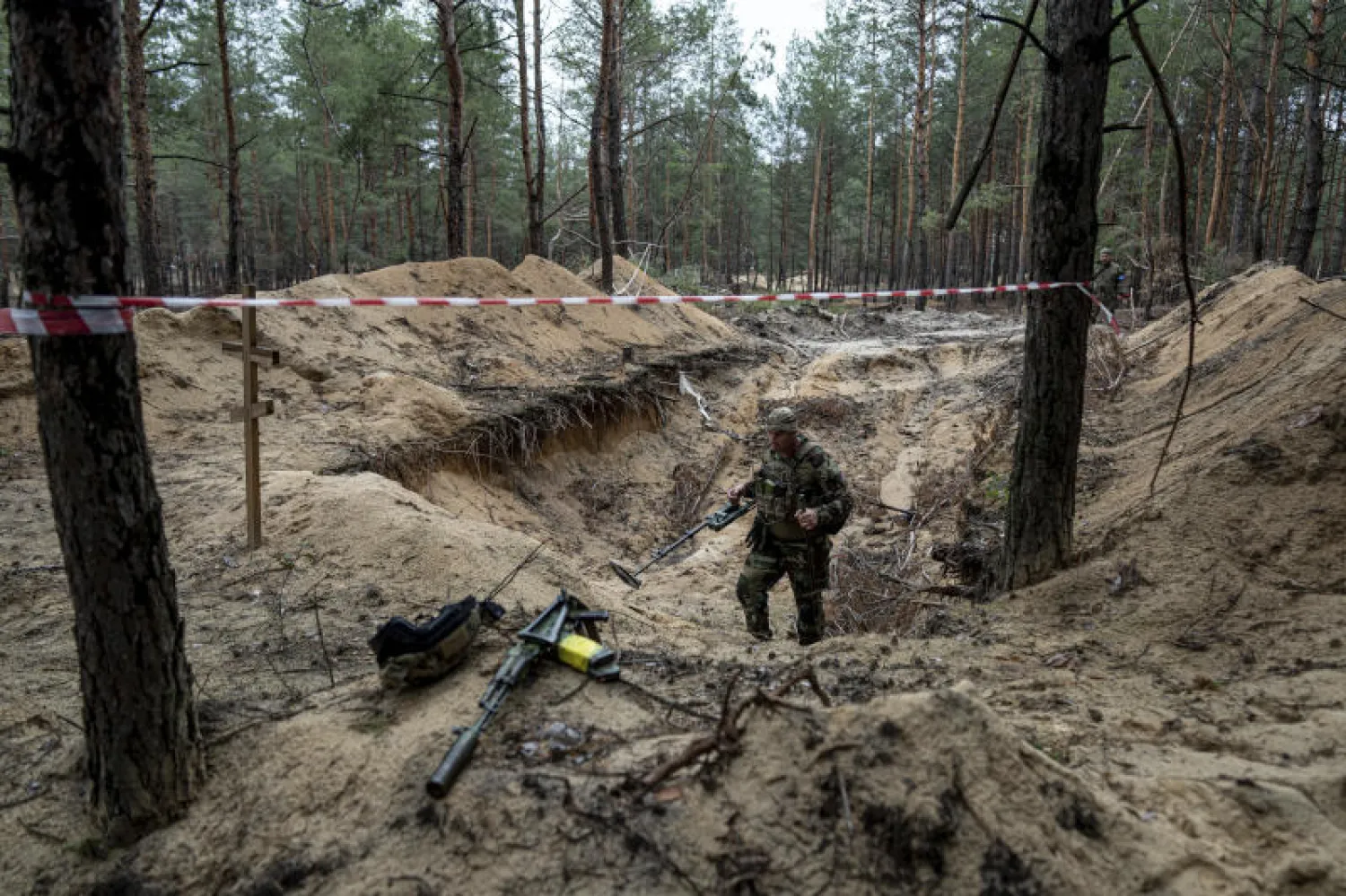 جندي أوكراني يستخدم كاشف معادان في ما يُعتقد أنها مقبرة جماعية في إيزيوم (أ.ب)
