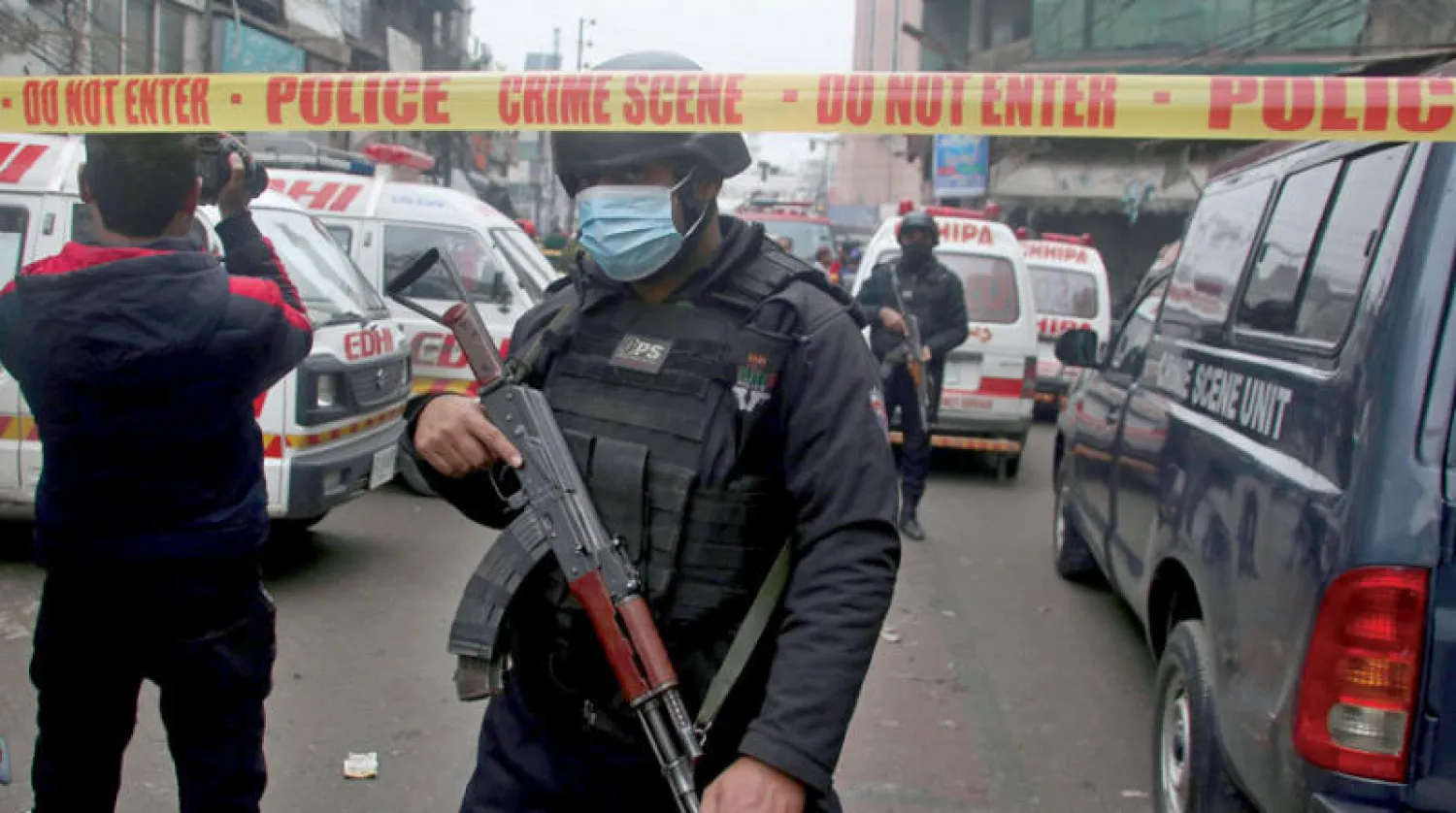 ضباط الشرطة يقفون في حراسة بينما تستعد سيارات الإسعاف لنقل أي جرحى من موقع انفجار قنبلة في لاهور يناير 2022 (أ.ب)