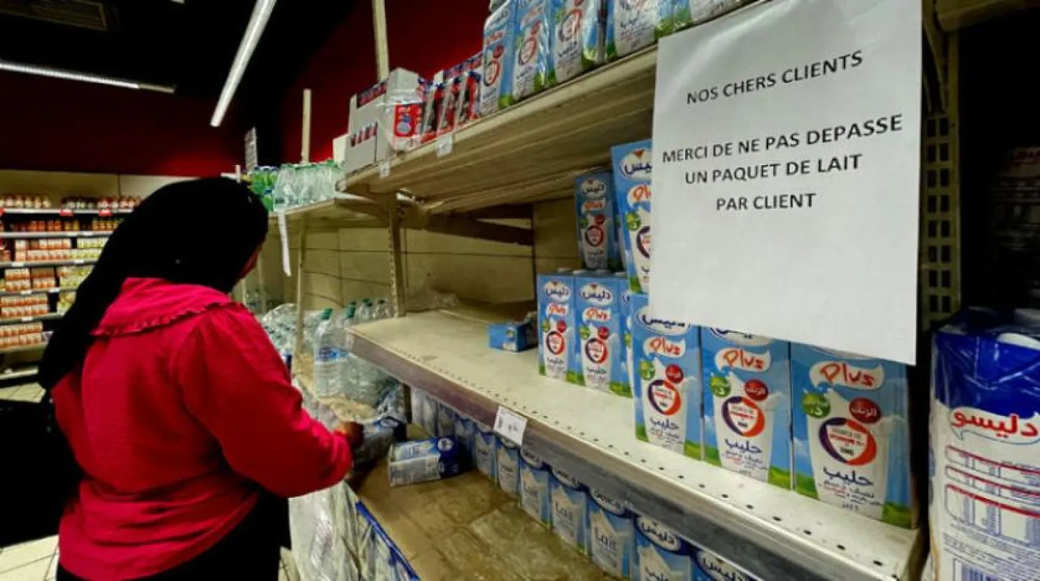 A Tunisian woman is shopping in a store, while the sign in French prohibits buying more than one bottle of milk per buyer (Reuters) 

