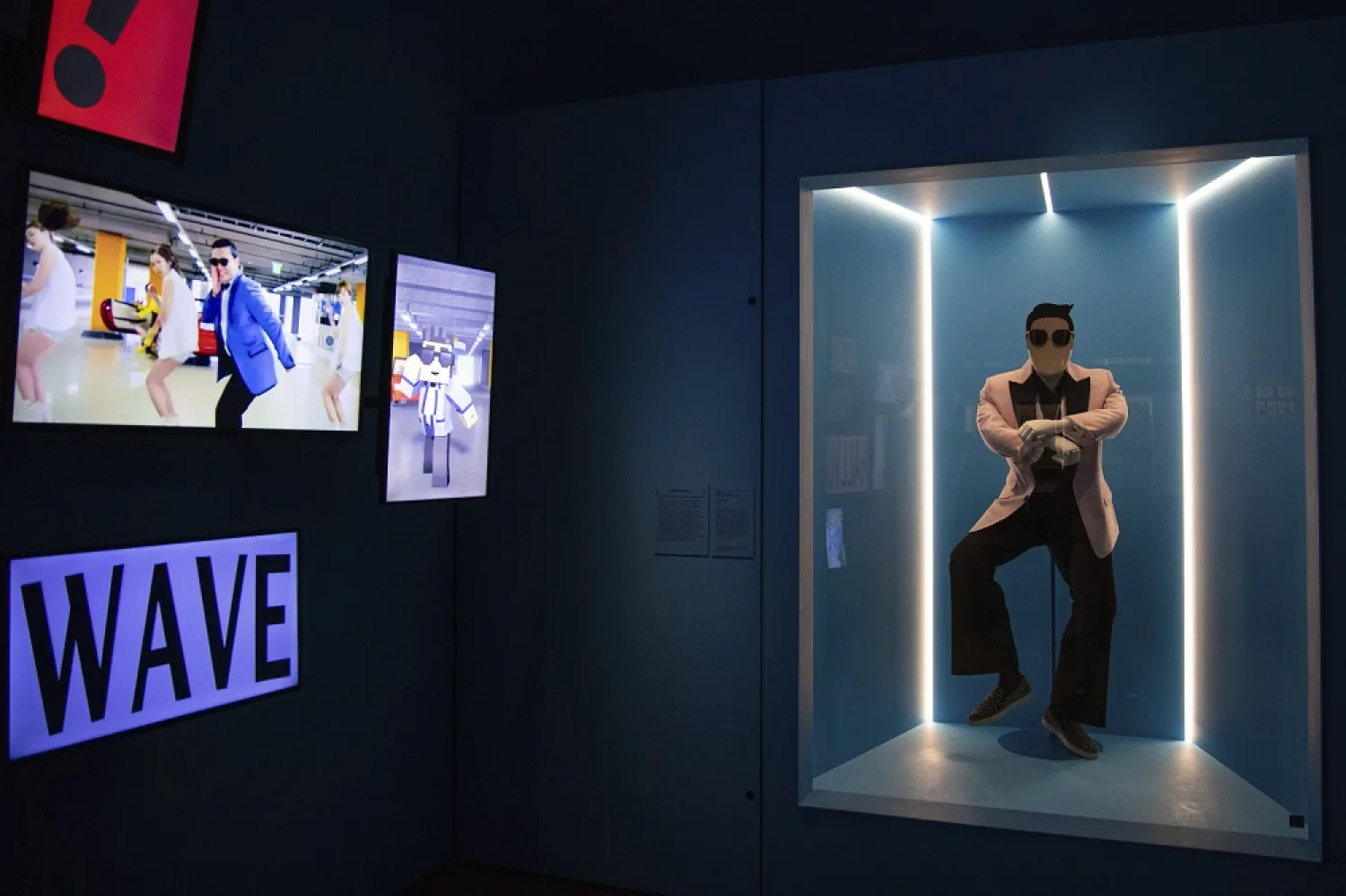 Multiple screens, left, show a music video of PSY's "Gangnam Style", alongside PSY's bubblegum pink jacket from the video, right, designed by Dsquared2, at the "Hallyu! The Korean Wave" exhibition at the Victoria and Albert museum in London, Wednesday, Sept. 21, 2022. (AP)