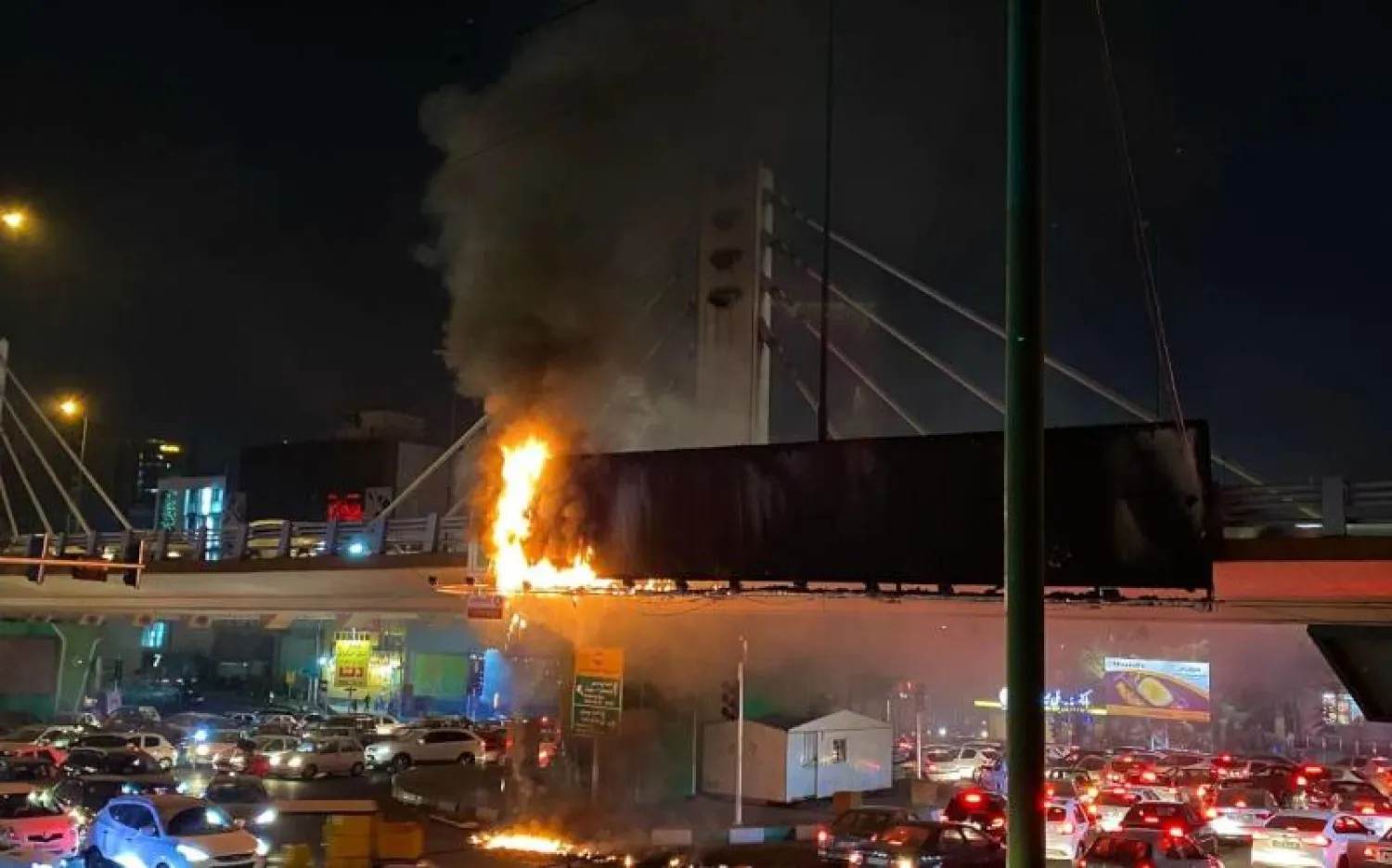 لوحة إلكترونية تحترق فوق جسر للمشاة في ميدان «ولي عصر» وسط طهران الأربعاء (تويتر)