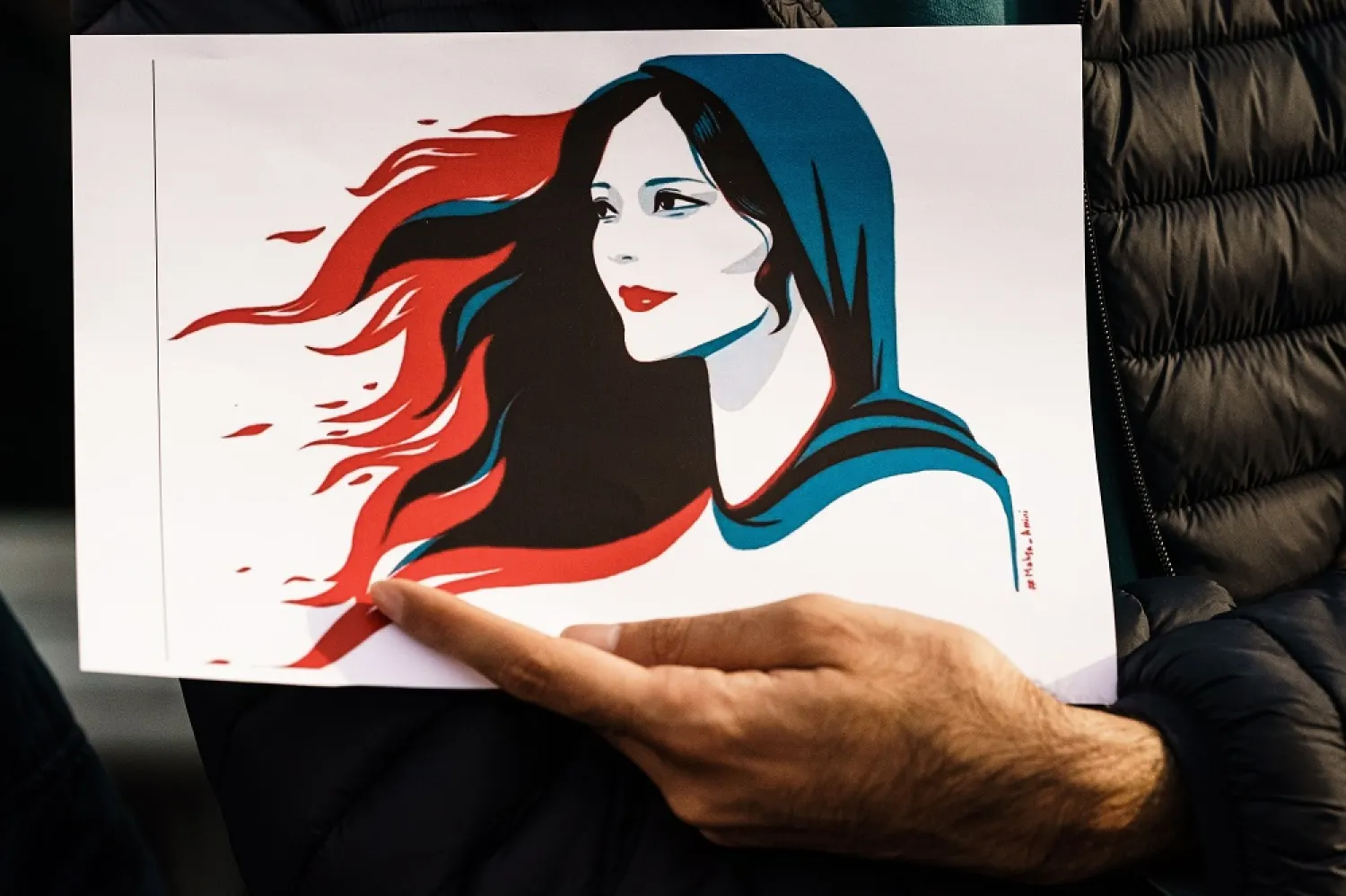 A participant holds an illustration showing Mahsa Amini during a rally in Berlin, Germany, 23 September 2022. (EPA)