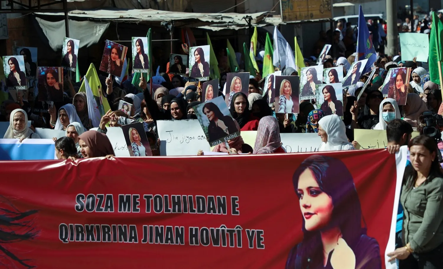 Women carry banners and pictures during a protest following the death of 22-year-old Kurdish woman Mahsa Amini in Iran, in the Kurdish-controlled city of Qamishli, northern Syria September 26, 2022. (Reuters)