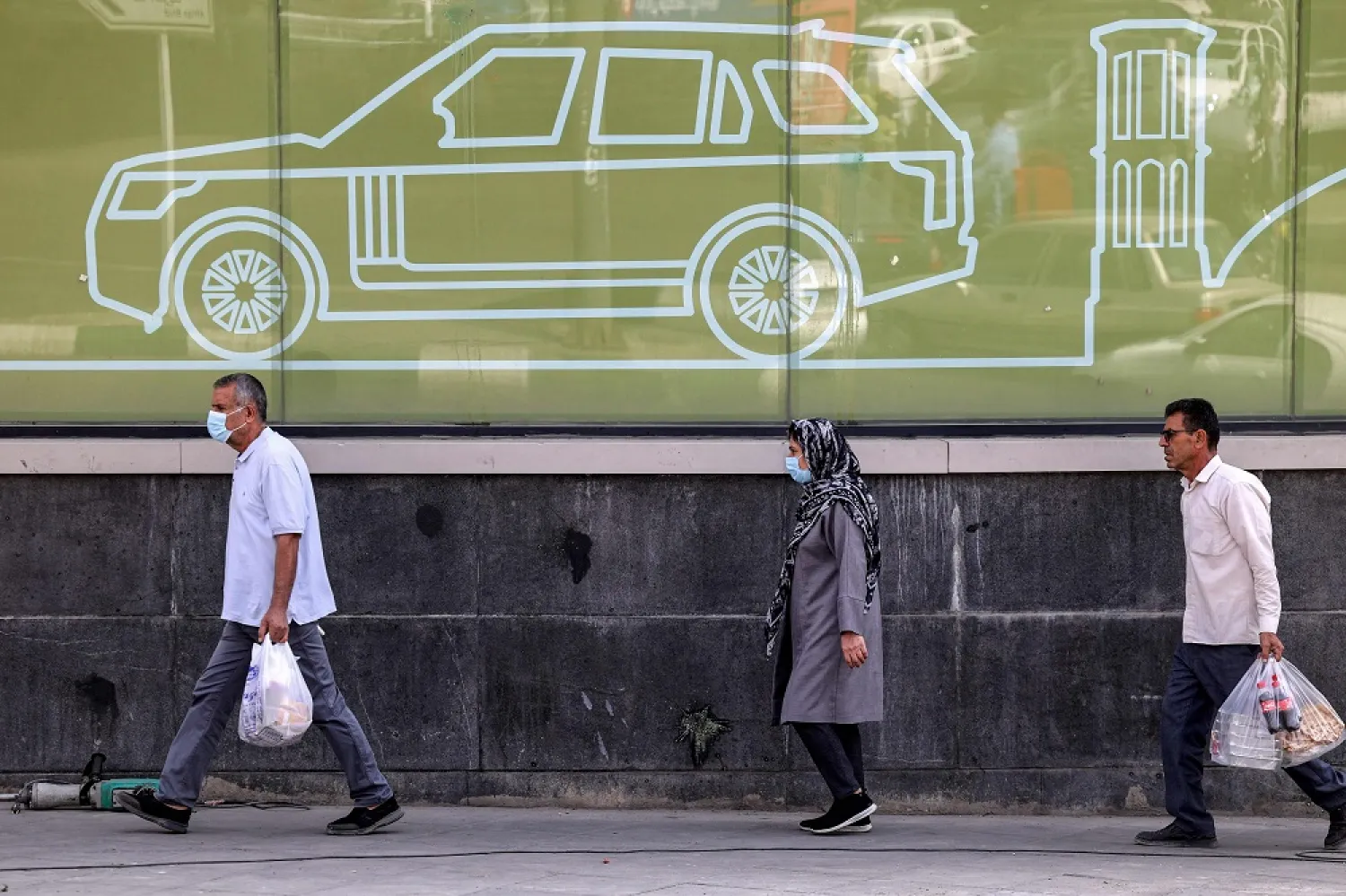 Men and a woman walk along the side of a road in the center of Iran's capital Tehran on September 26, 2022. (Reuters)