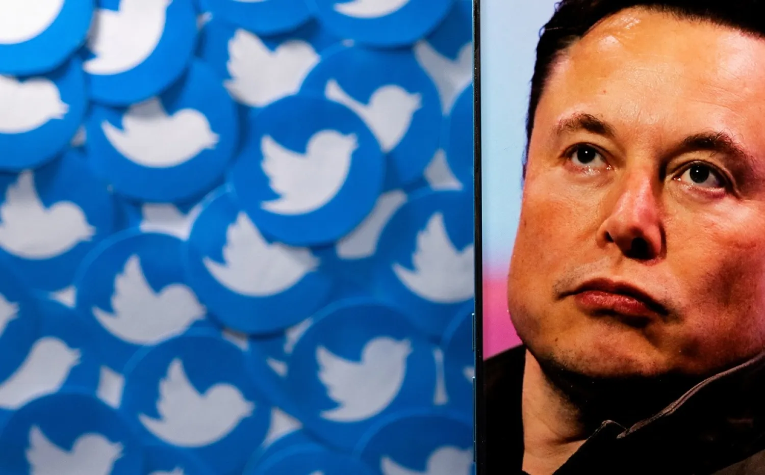 An image of Elon Musk is seen on a smartphone placed on printed Twitter logos in this picture illustration taken April 28, 2022. (Reuters)