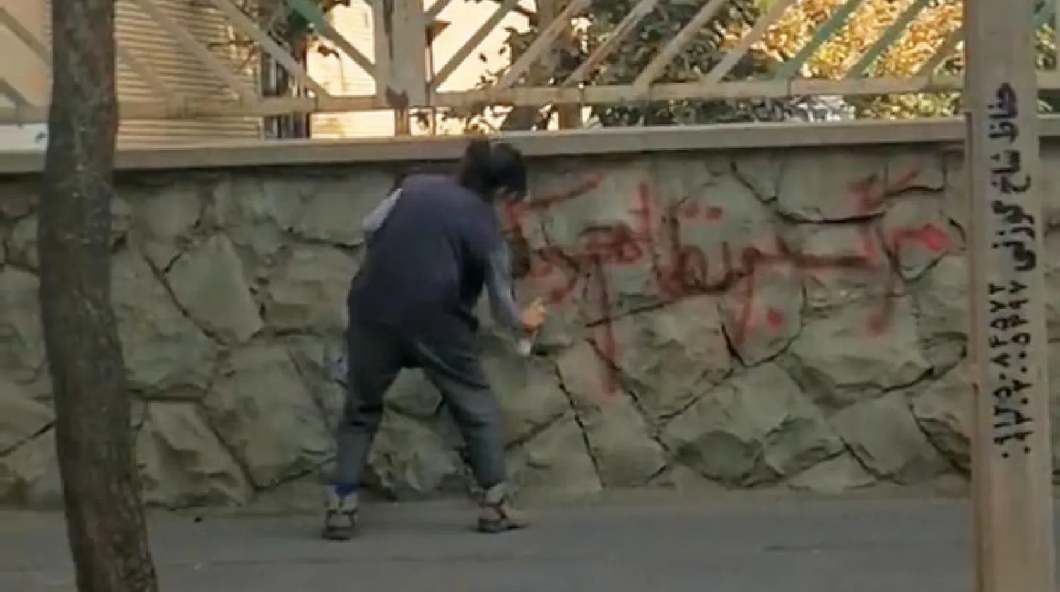 إيرانية تكتب شعار «الموت للنظام الدكتاتوري» على حائط في طهران (تويتر)