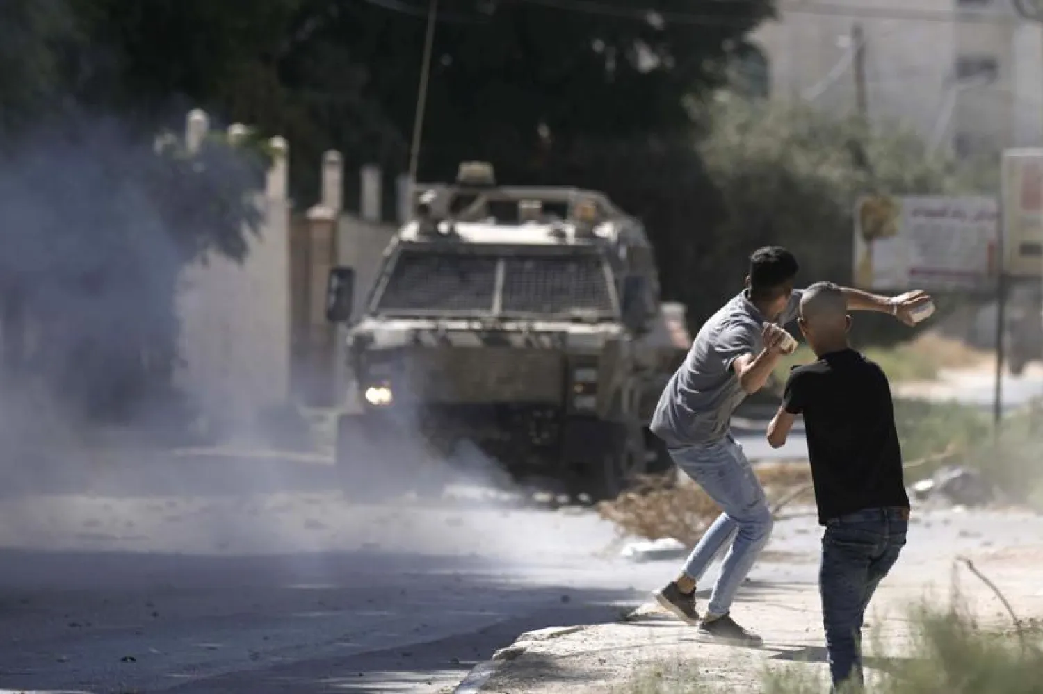 A Palestinian throws stones at an Israeli military vehicle following a deadly raid in the occupied West Bank town of Jenin, Wednesday, Sept. 28, 2022 - (AP Photo/Majdi Mohammed)
