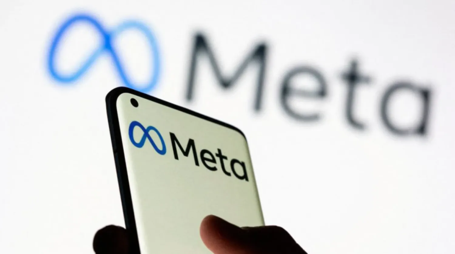 A woman holds a smartphone with Meta logo in front of a displayed Facebook's new rebrand logo Meta in this illustration picture taken October 28, 2021. REUTERS/Dado Ruvic/Illustration/File Photo/File Photo
