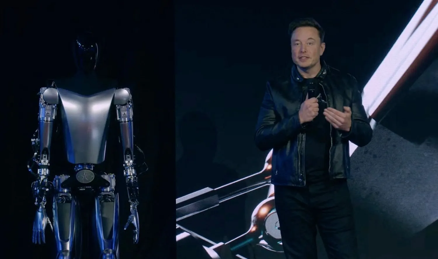 This video screen grab made from Tesla AI Day 2022 livestream shows Elon Musk standing on stage next to Optimus the humanoid robot in Palo Alto, California on September 30, 2022. (AFP/ Handout/ Tesla)