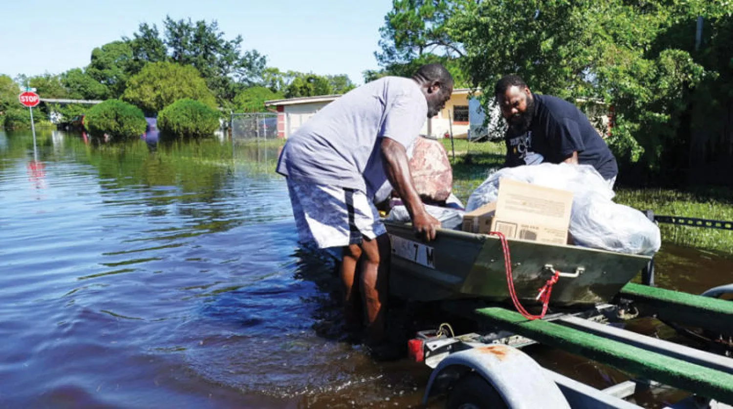 أميركيان ينقلان أمتعتهما بعد إعصار إيان في أورلاندو أمس (أ.ف.ب)