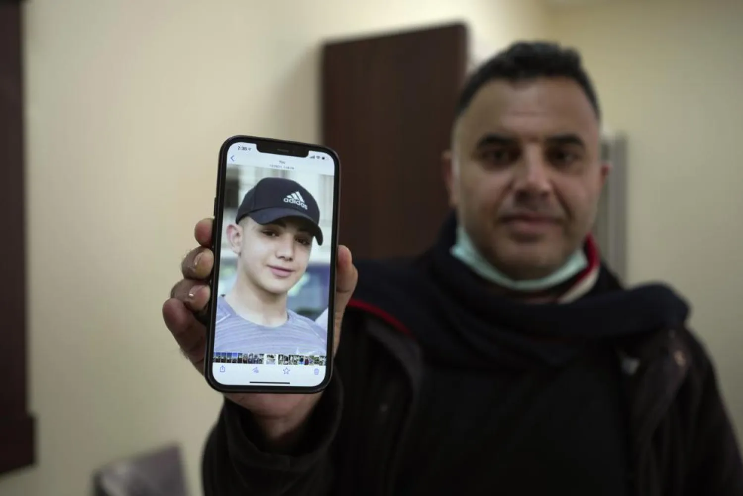FILE - Muamar Nakhleh, father of Amal Nakhleh, a Palestinian teen with a rare neuromuscular disorder, who had been held without charge for a year, shows his photo at his office, in the West Bank city of Ramallah, Jan, 10, 2022.  (AP Photo/Majdi Mohammed, File)
