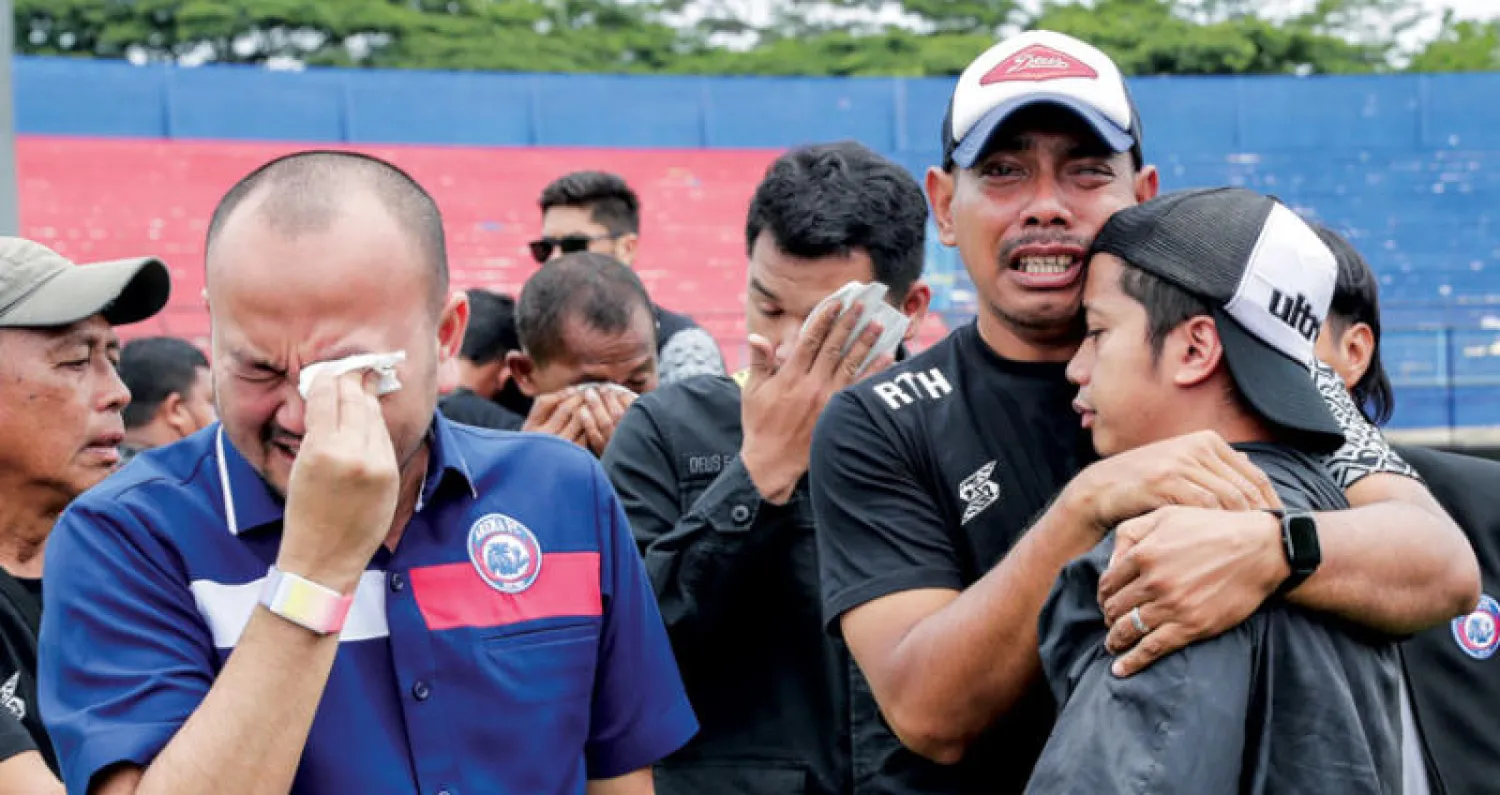 أقارب للضحايا يبكون داخل الملعب الذي شهد الحادثة المأساوية (إ.ب.أ)