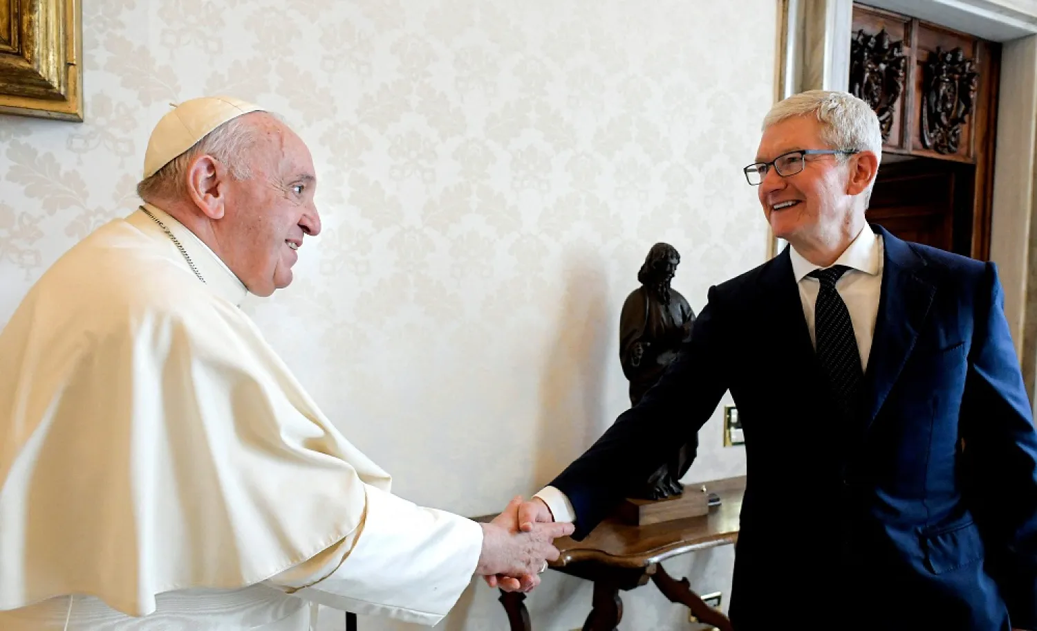 This handout photo taken on October 3, 2022 and released by the Vatican press office, the Vatican Media, shows Pope Francis (L) shaking hands with Apple CEO Tim Cook prior to a private audience at the Vatican. (Vatican Media/AFP)