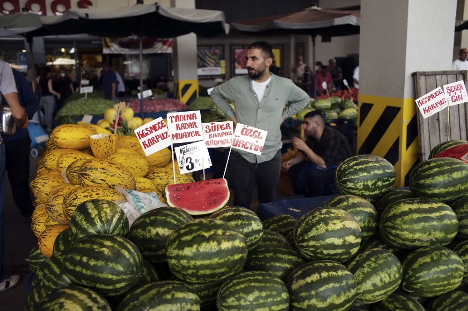 A man waits for clients at an open air food market, in Ankara, Türkiye, Sunday, July 31, 2022. (AP)