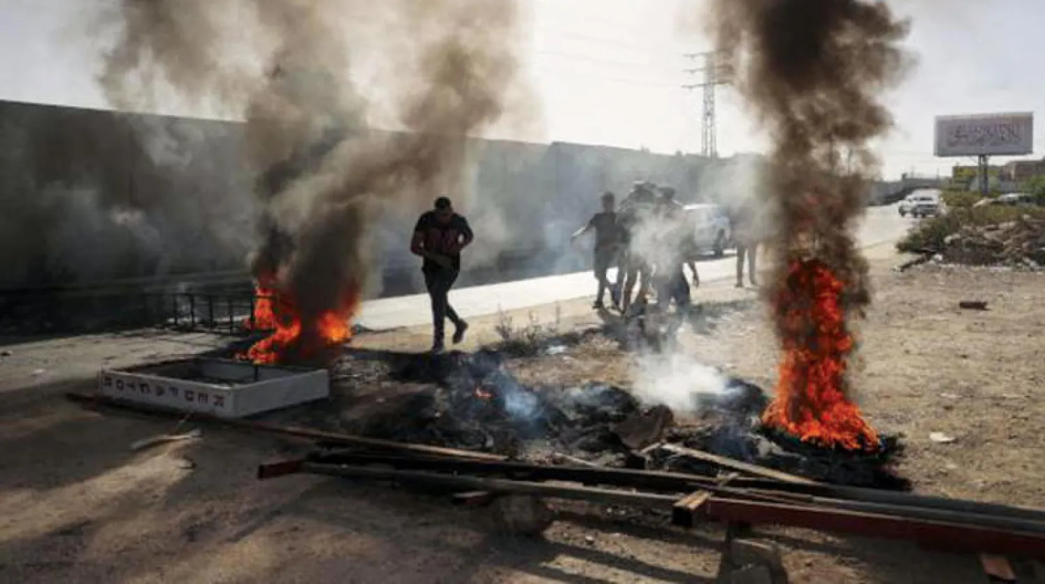 حرق إطارات سيارات قرب مستوطنة بيت إيل بعد قتل إسرائيل فلسطينيين من مخيم الجلزون (أ.ف.ب)