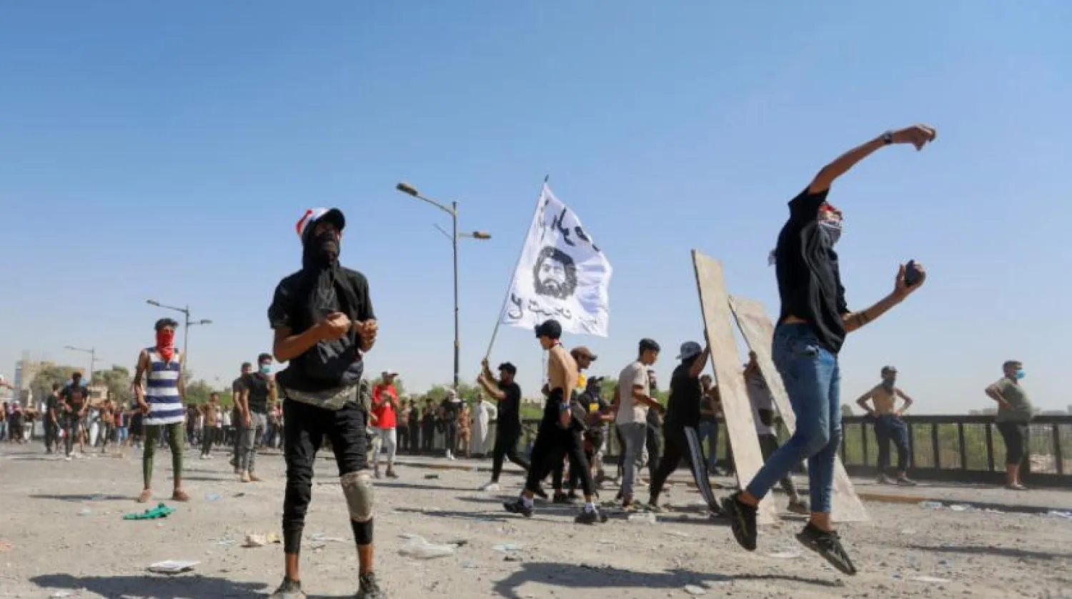 
یکی از تظاهر کنندگان در سالروز اعتراضات اکتبر به سمت ماموران امنیتی عراق سنگ پرتاب می کند (رویترز)