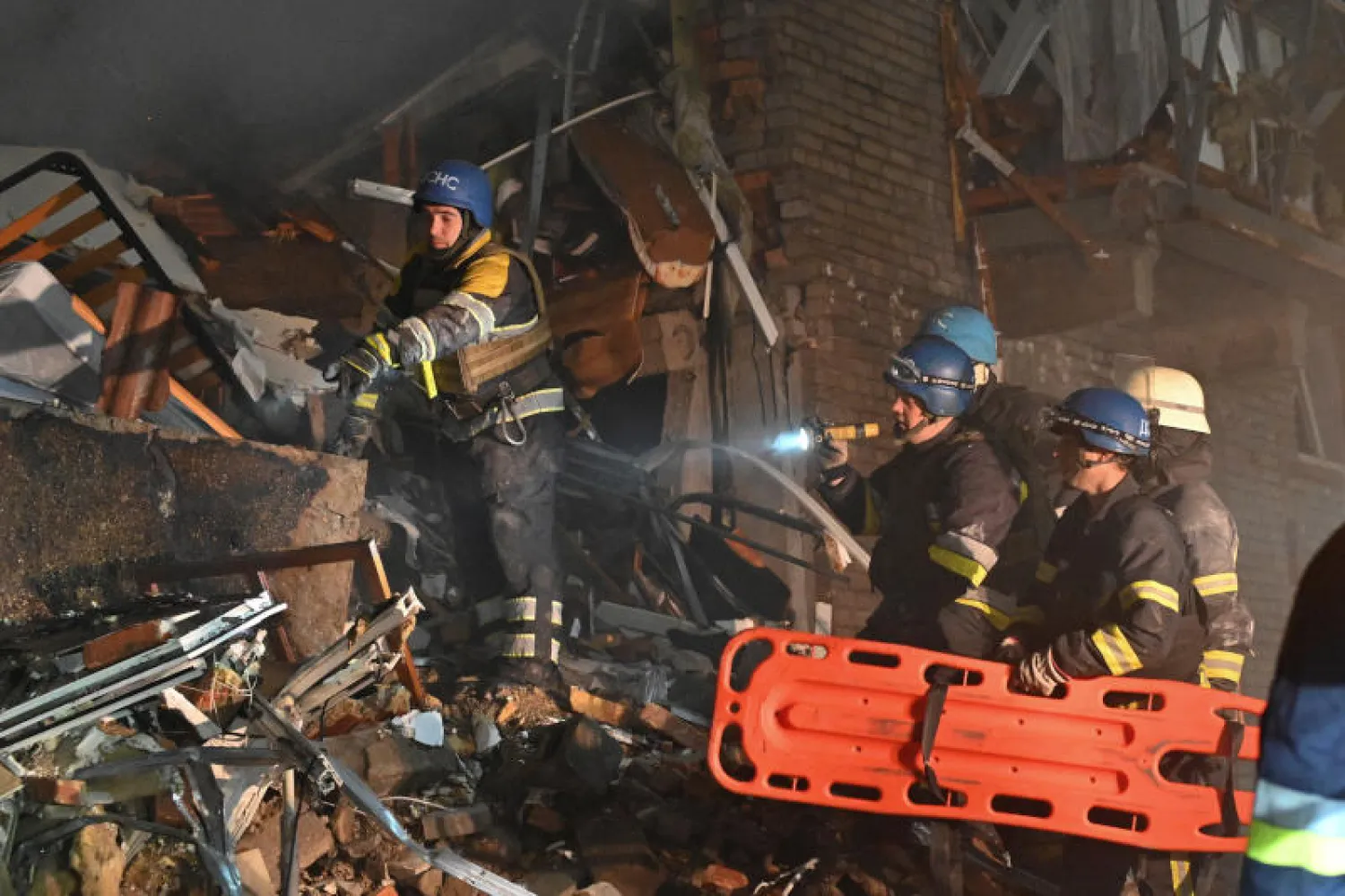 عمال الإنقاذ يعملون في موقع مبنى سكني تضرر بشدة من هجوم صاروخي روسي في زابوريجيا (رويترز)