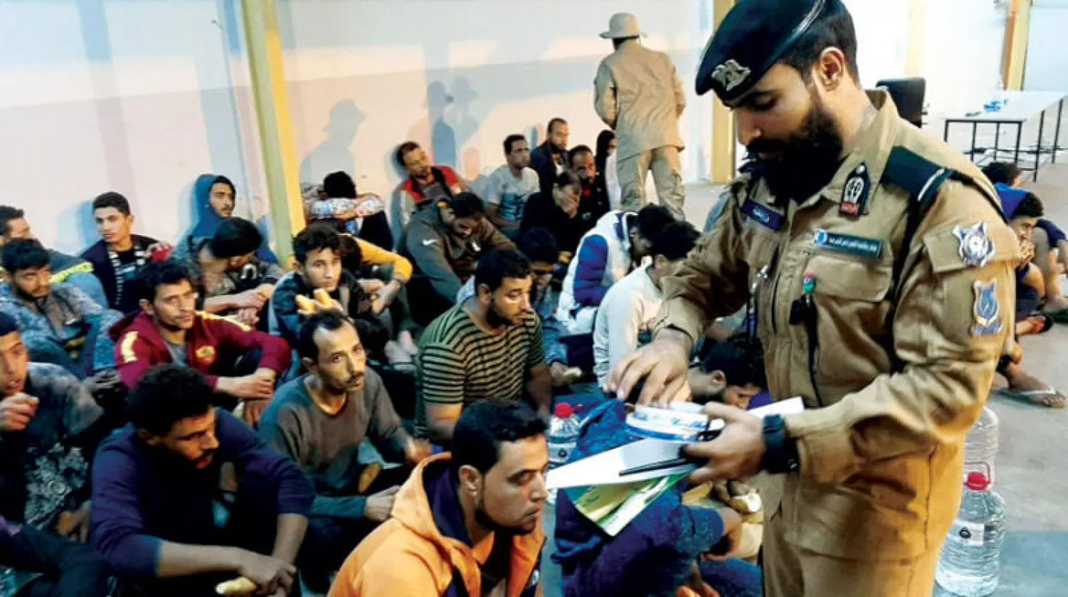 رجل أمن ليبي يجمع وثائق عدد من المهاجرين في طرابلس (أرشيفية من جهاز مكافحة الهجرة غير المشروعة)