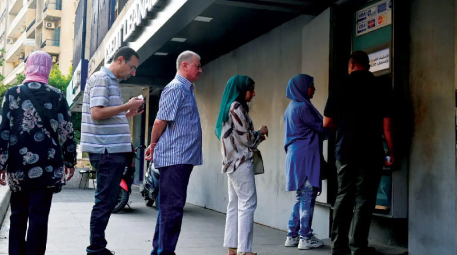 مواطنون أمام آلة لسحب النقود بعدما أغلقت مصارف لبنان أبوابها اعتباراً من 7 أكتوبر في ظل تكرر حوادث اقتحام فروعها من مودعين يطالبون باسترداد مستحقاتهم (إ.ب.أ)