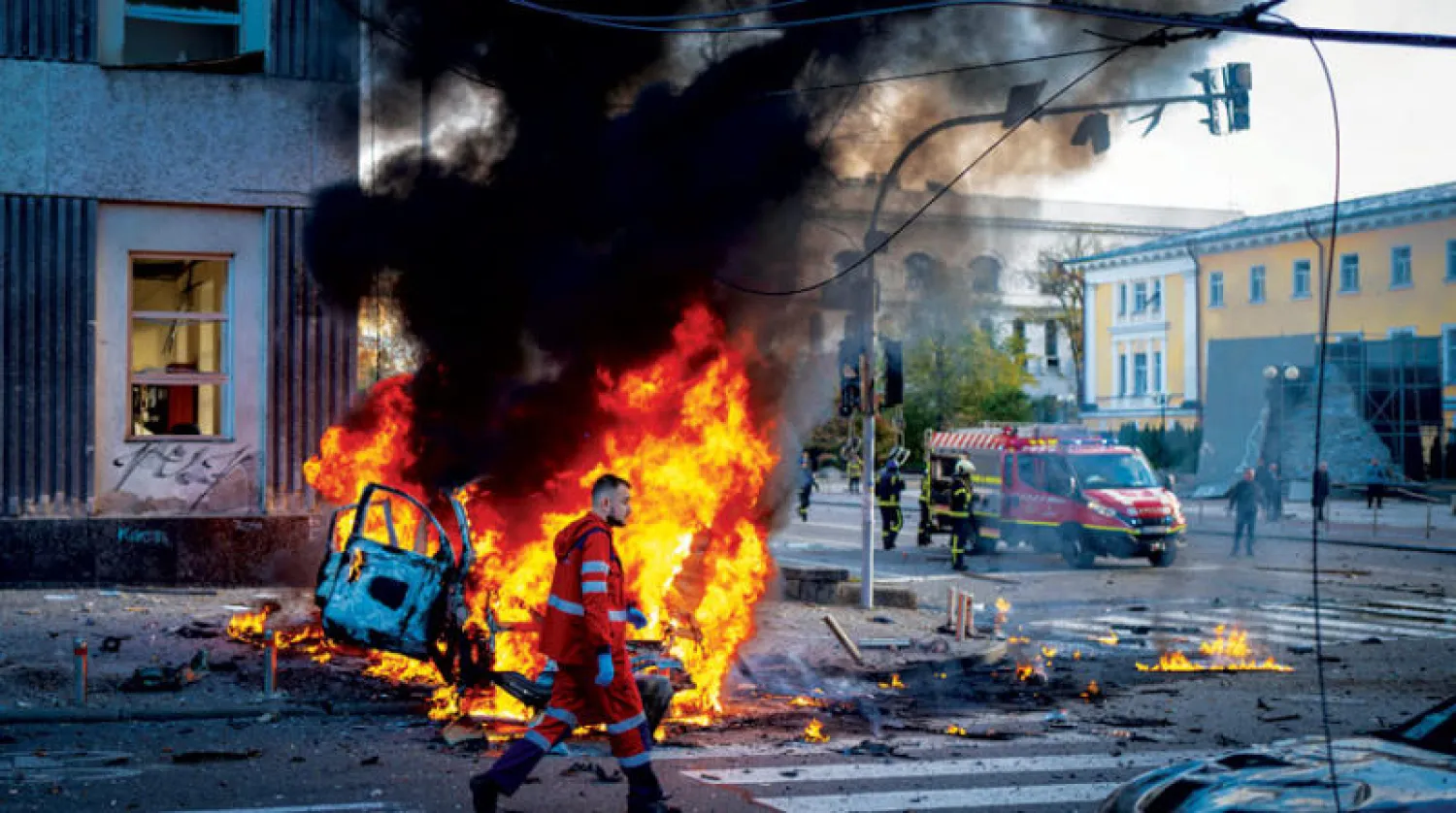 عنصر طبي يسير أمام سيارة محترقة بعد القصف الروسي في كييف أمس (أ.ب)