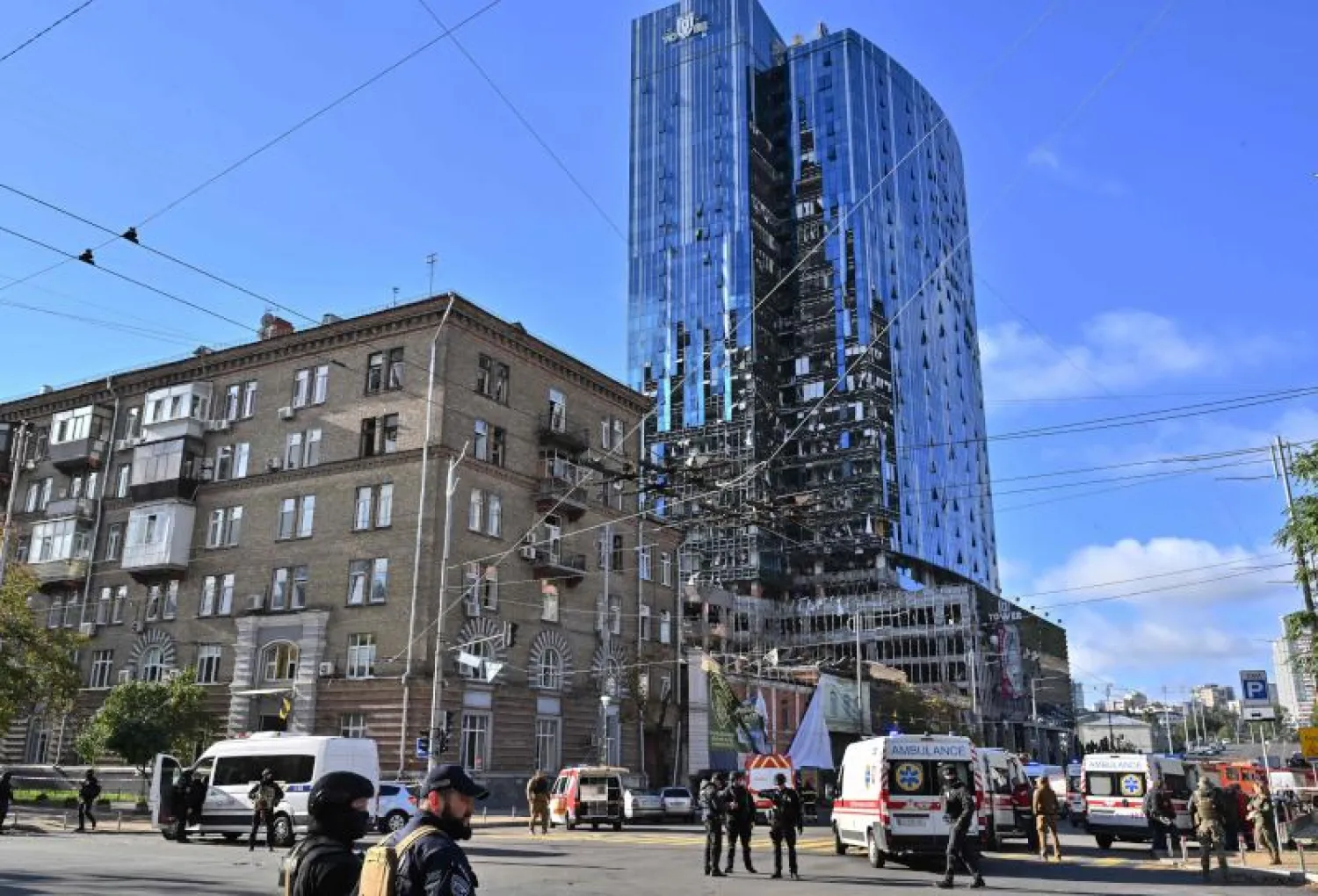 أفراد الشرطة وخدمة الطوارئ قرب مبنى دُمّر جزئيا جراء القصف الصاروخي على كييف (أ.ف.ب)