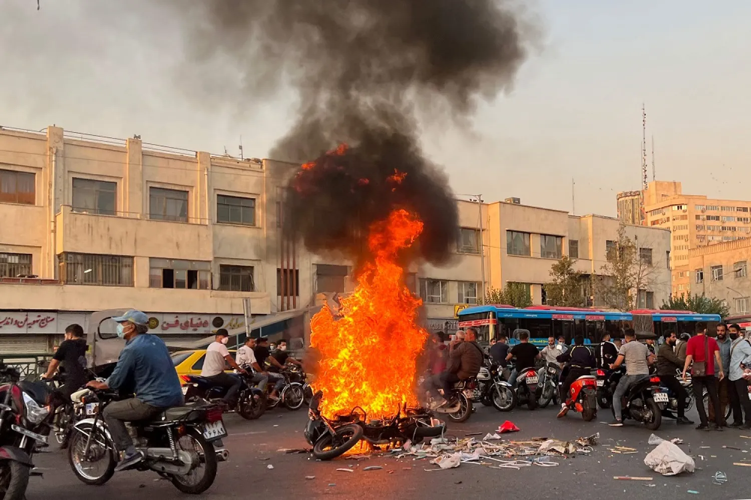 A picture obtained by AFP outside Iran, shows people gathering next to a burning motorcycle in the capital Tehran on October 8, 2022. (AFP)