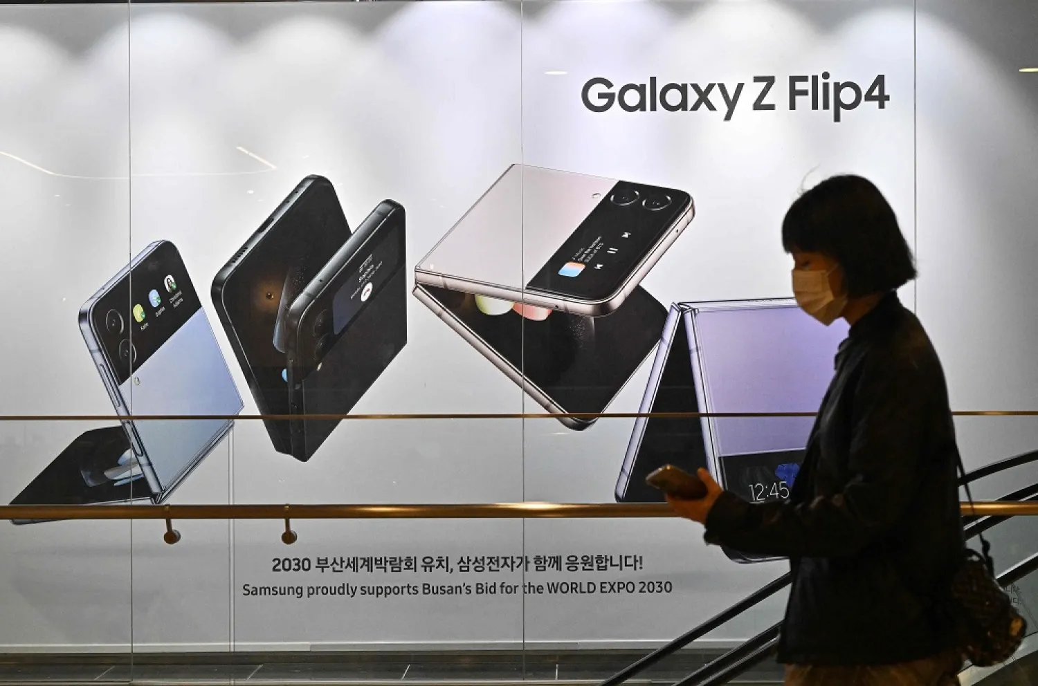 A woman walks past an advertisement for the Samsung Galaxy Z Flip4 smartphone at the company's Seocho building in Seoul on October 7, 2022. (AFP)