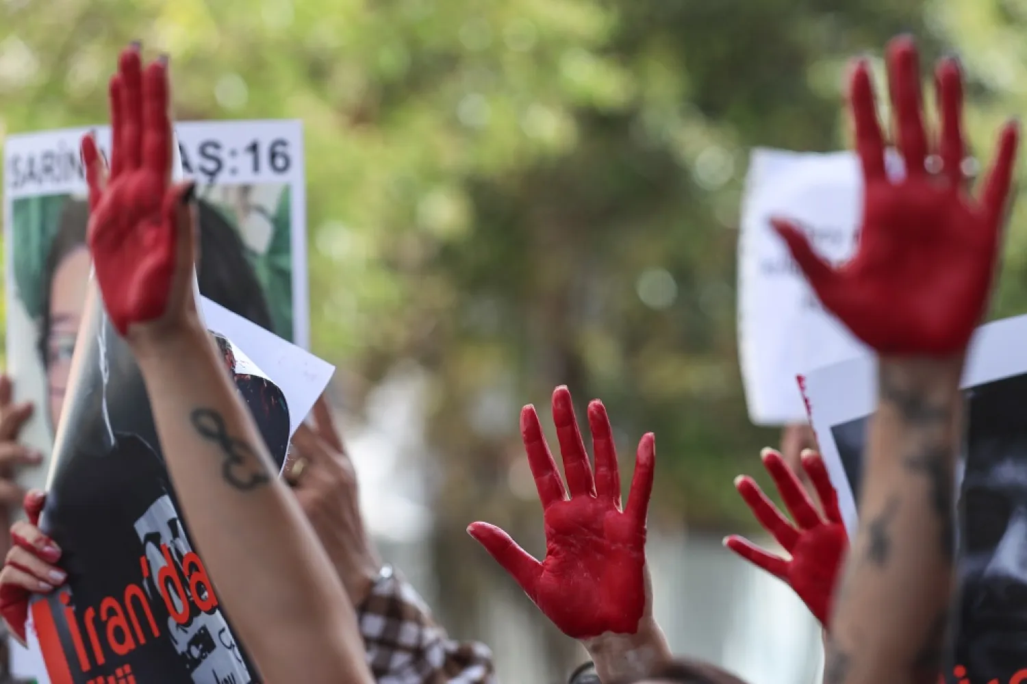 Iranian people hold pictures of Mahsa Amini with their hands painted in red during a protest outside the Iranian Consulate following the death of Mahsa Amini, in Istanbul, Türkiye, 11 October 2022. (EPA)