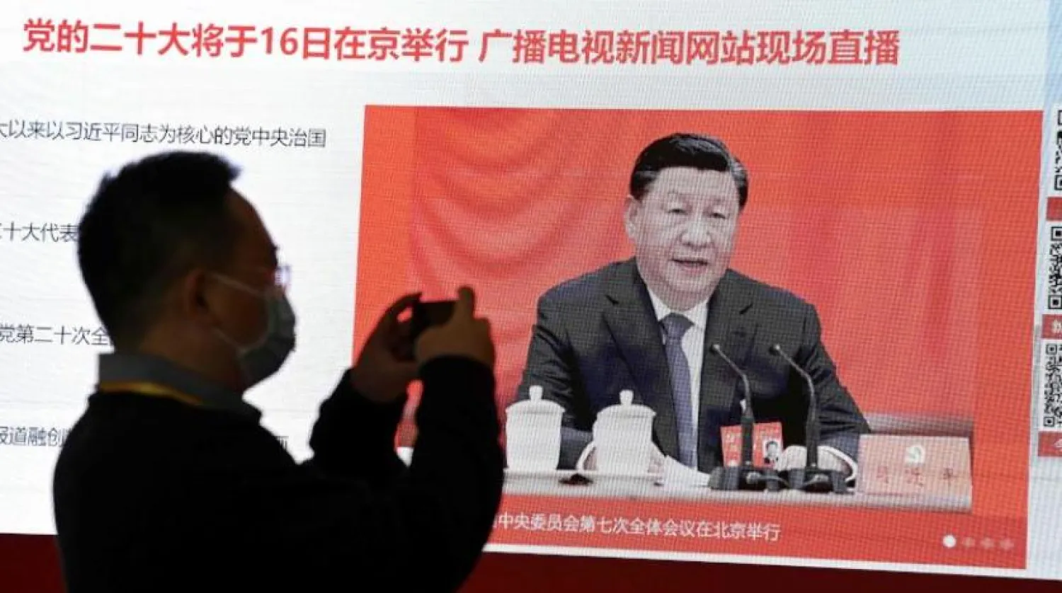 Bir gazeteci Çin Devlet Başkanı Cinping'i gösteren bir ekranın fotoğrafını çekiyor (AFP) 
