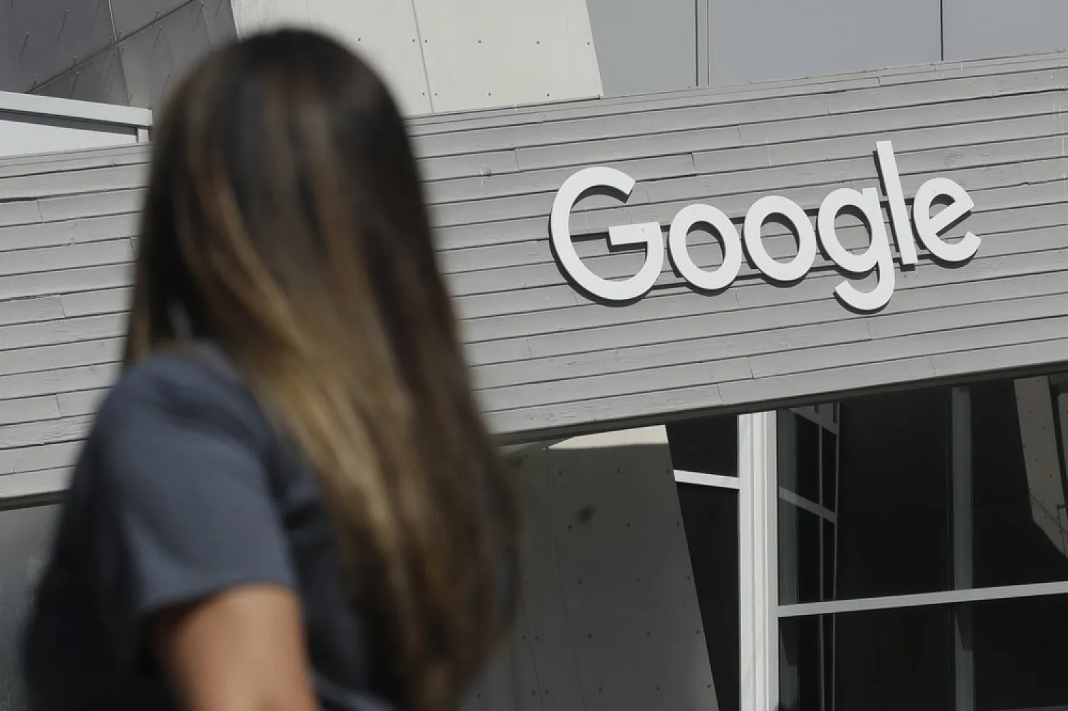 FILE - In this Sept. 24, 2019, file photo, a woman walks below a Google sign on the campus in Mountain View, Calif. (AP Photo/Jeff Chiu, File)
