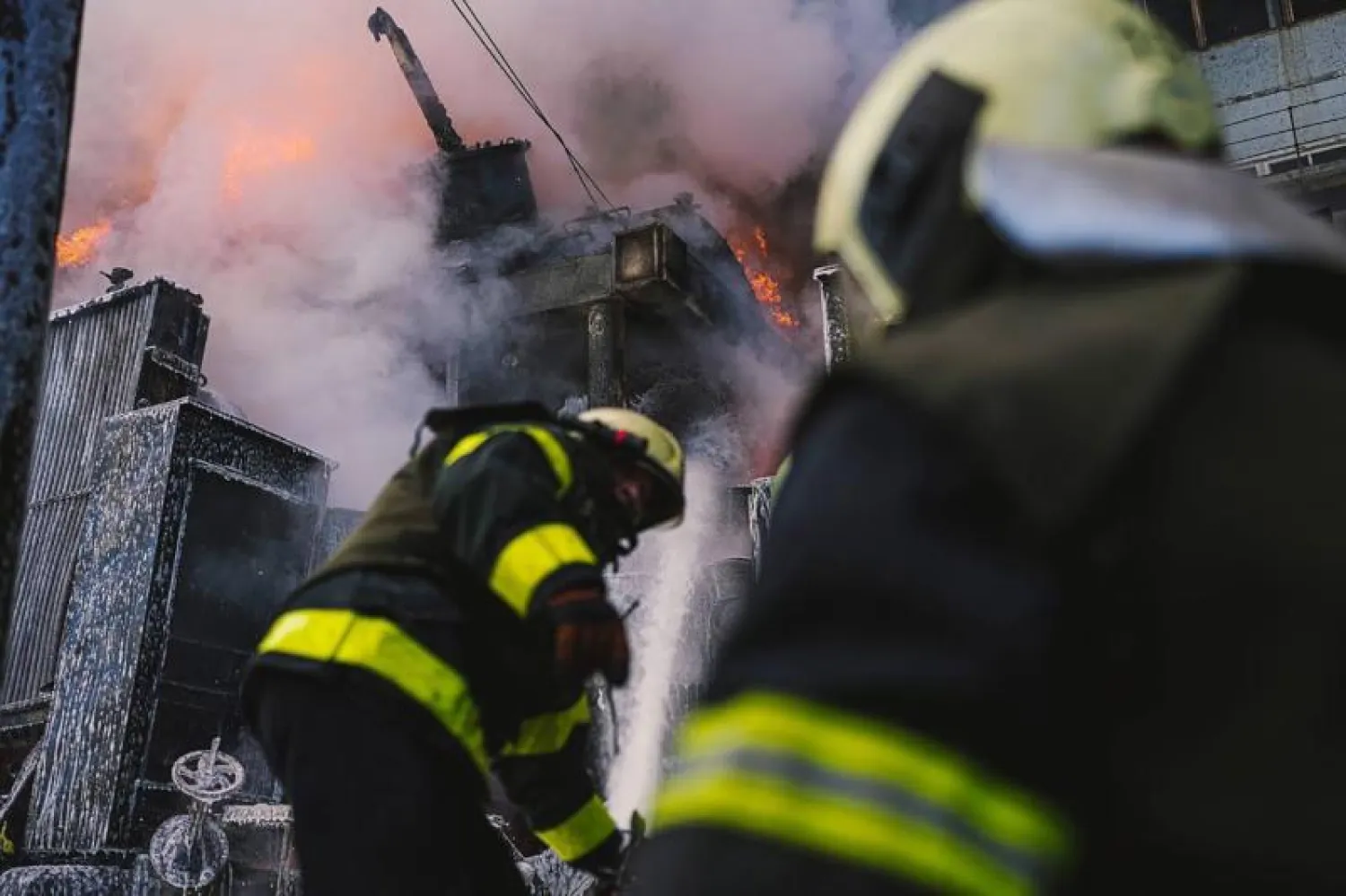 إطفائيان يكافحان النار بعد قصف روسي لكييف (إ.ب.أ)