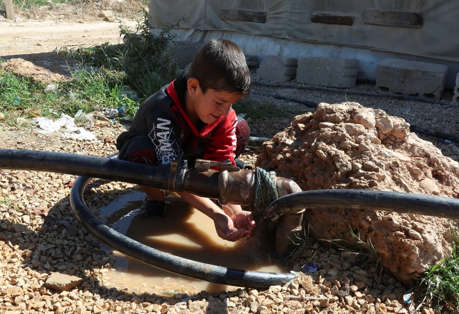 A Syrian refugee boy washes himself at an informal camp in Qob Elias, in Lebanon's Bekaa Valley October 18, 2022. (Reuters)