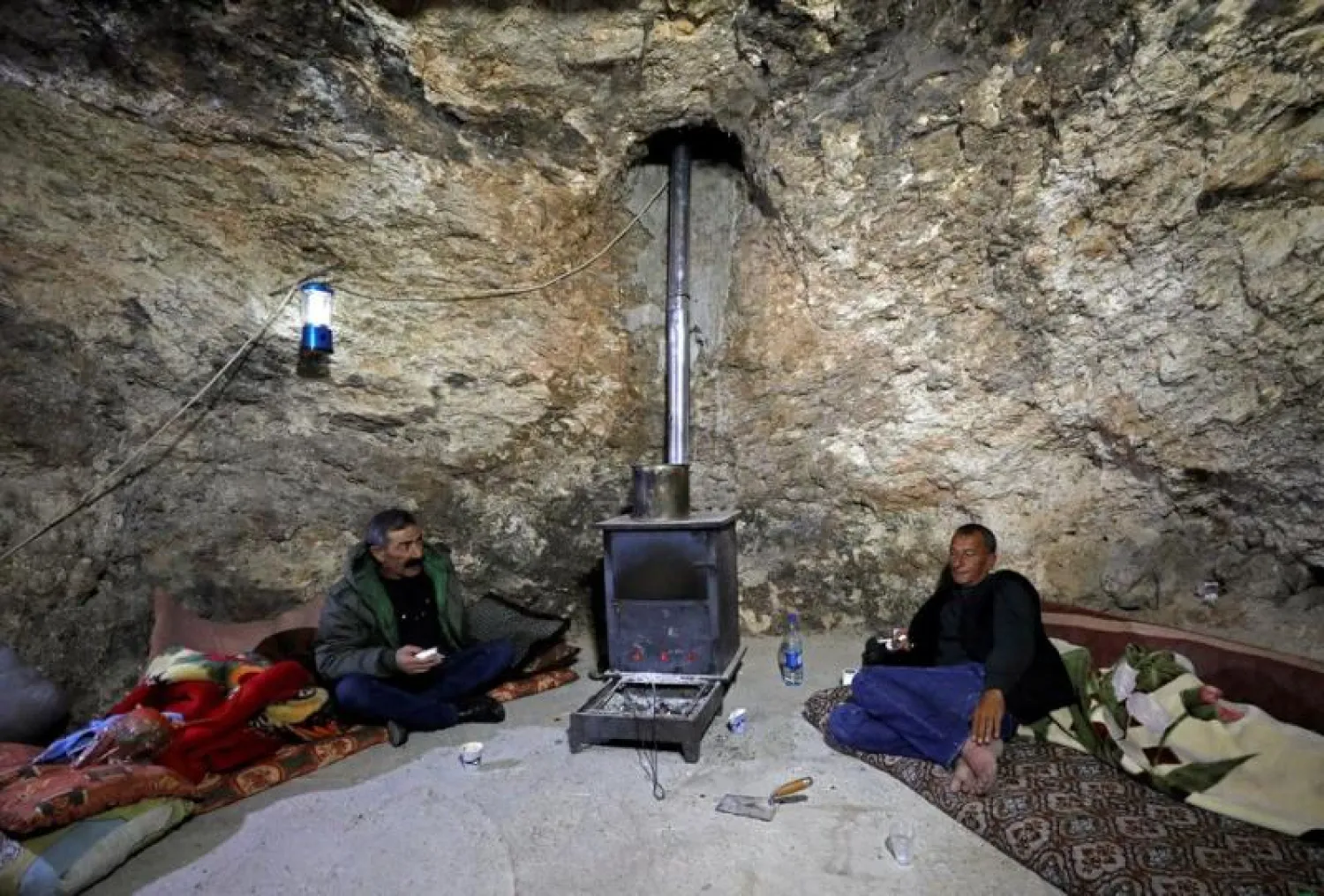 فلسطينيان يجلسان في كهف بمنطقة مسافر يطّا (رويترز)