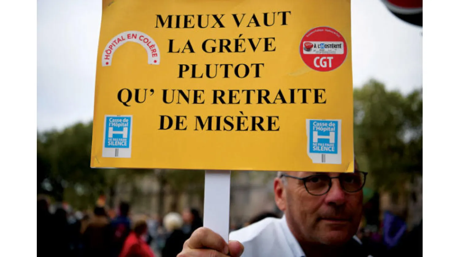 فرنسي يحمل لافتة كتب عليها «إن الإضراب أفضل من التقاعد البائس» خلال مظاهرة في باريس قبل أيام (أ.ف.ب)