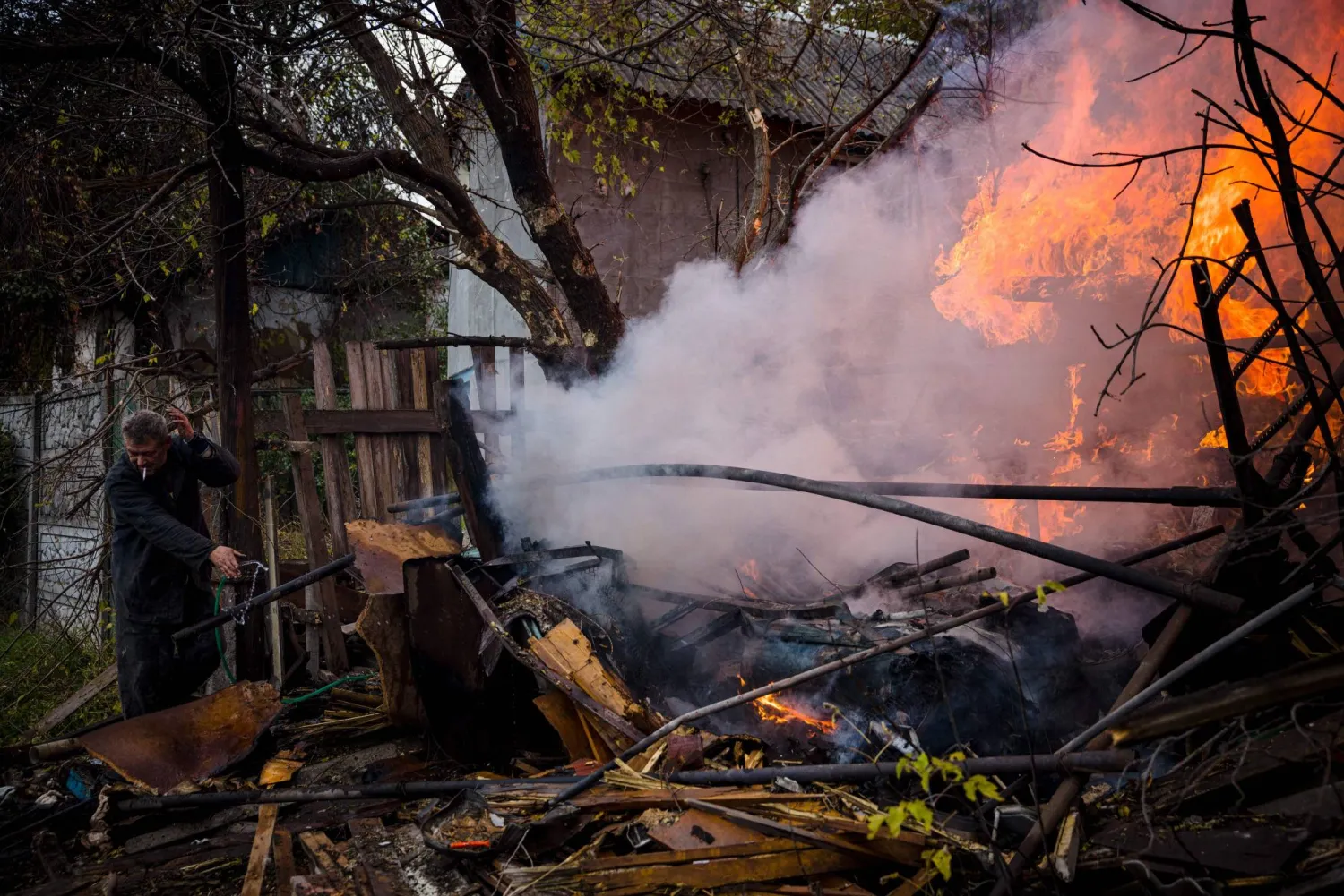 A local resident works to extinguish a fire after shelling on Sunday in the town of Bakhmut, in eastern Ukraine's Donbas region. | AFP-JIJI
