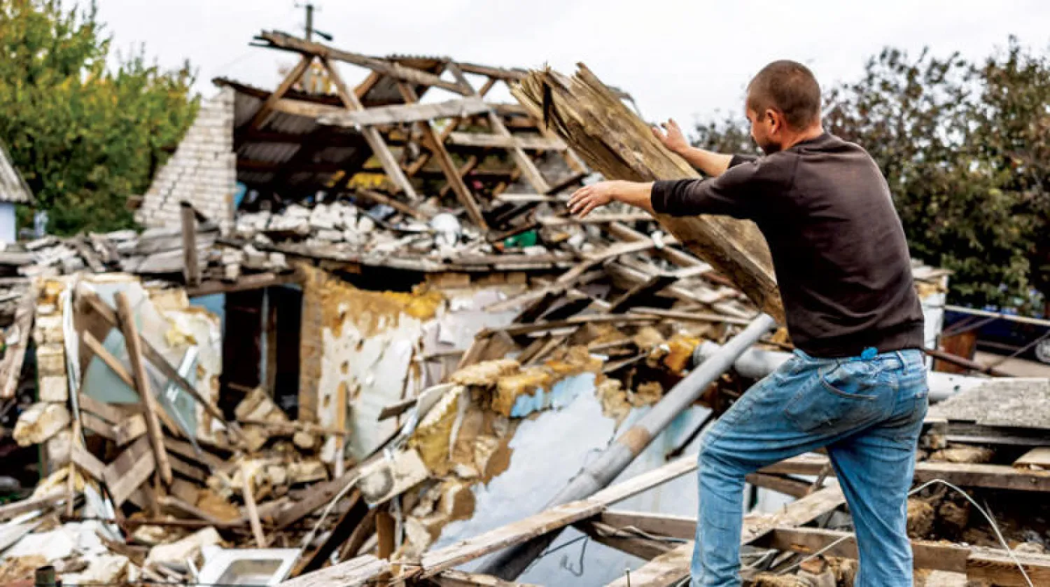 أوكراني يحاول ترميم منزله في قرية قرب خيرسون بعد أن استعادتها القوات الأوكرانية (إ.ب.أ)