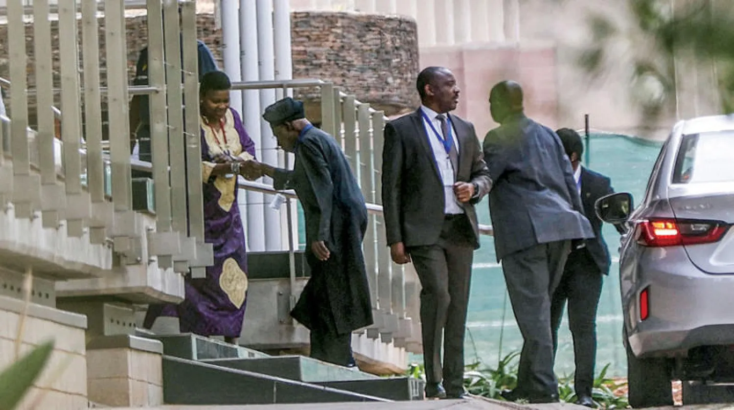 أوباسانجو يصافح مسؤولة لدى دخوله إلى مكان المحادثات بين إثيوبيا وتيغراي في بريتوريا الجنوب أفريقية أمس (أ.ف.ب)