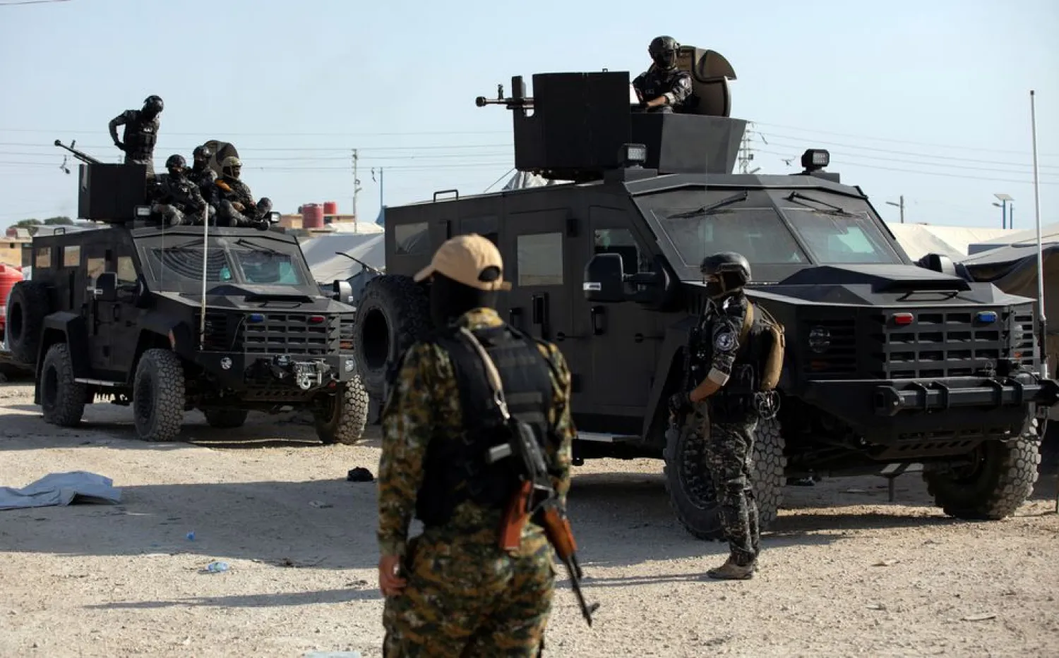 A Syrian Democratic Forces (SDF) fighter stands near Kurdish internal security special forces during a security operation in al-Hol camp which holds displaced people and families of ISIS militants in Hasaka governorate, in northeast Syria August 26, 2022. REUTERS/Orhan Qereman