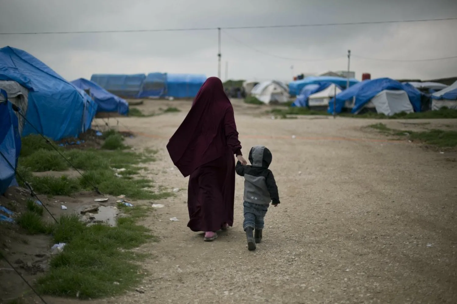 In this March 27, 2019, photo, Samira from Belgium walks with her son at Camp Roj in north Syria. (AP Photo/Maya Alleruzzo)