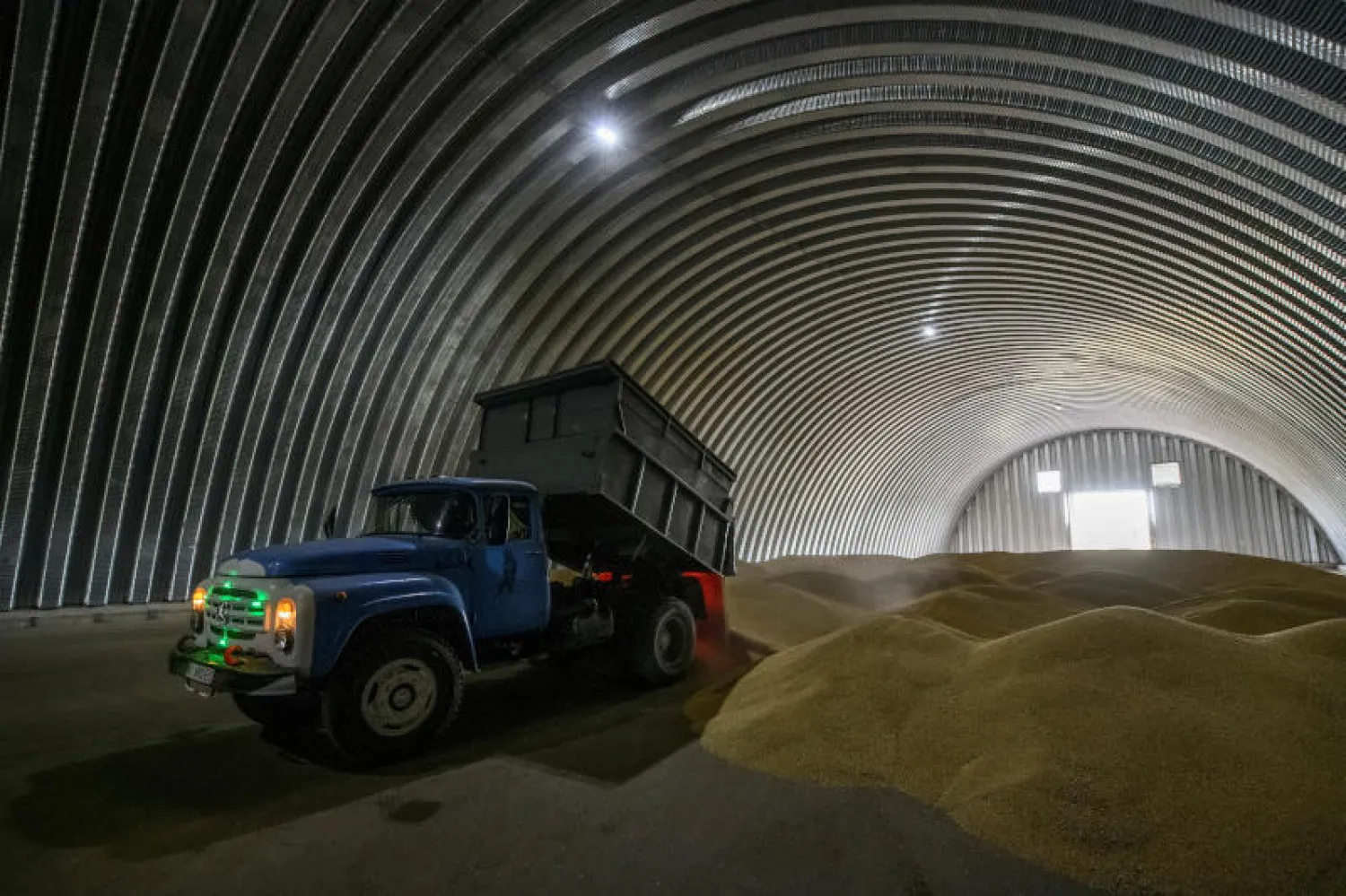 عامل يفرغ حبوب القمح داخل مخزن في قرية زغوريفكا وسط هجوم روسيا على أوكرانيا في كييف (رويترز)